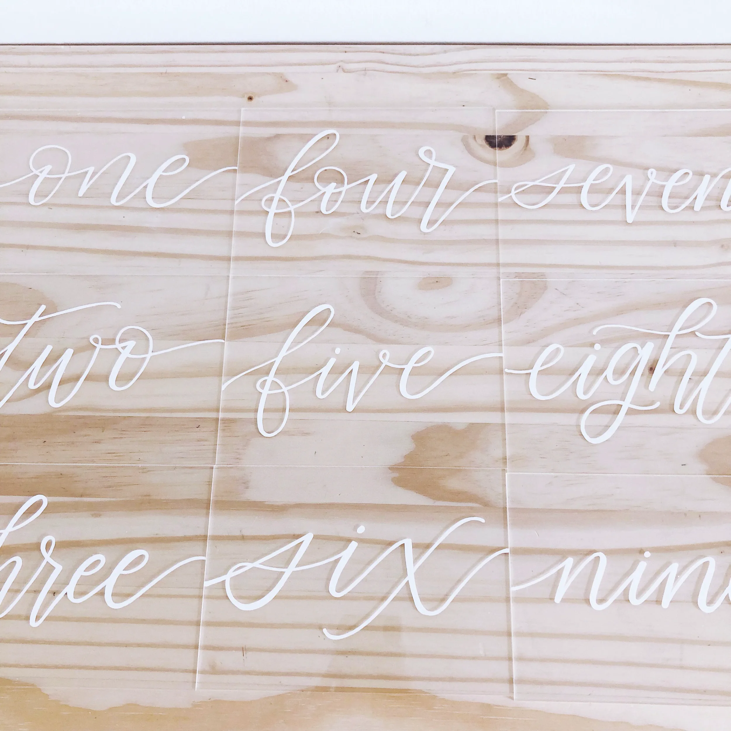 Clear acrylic table numbers in white script calligraphy.