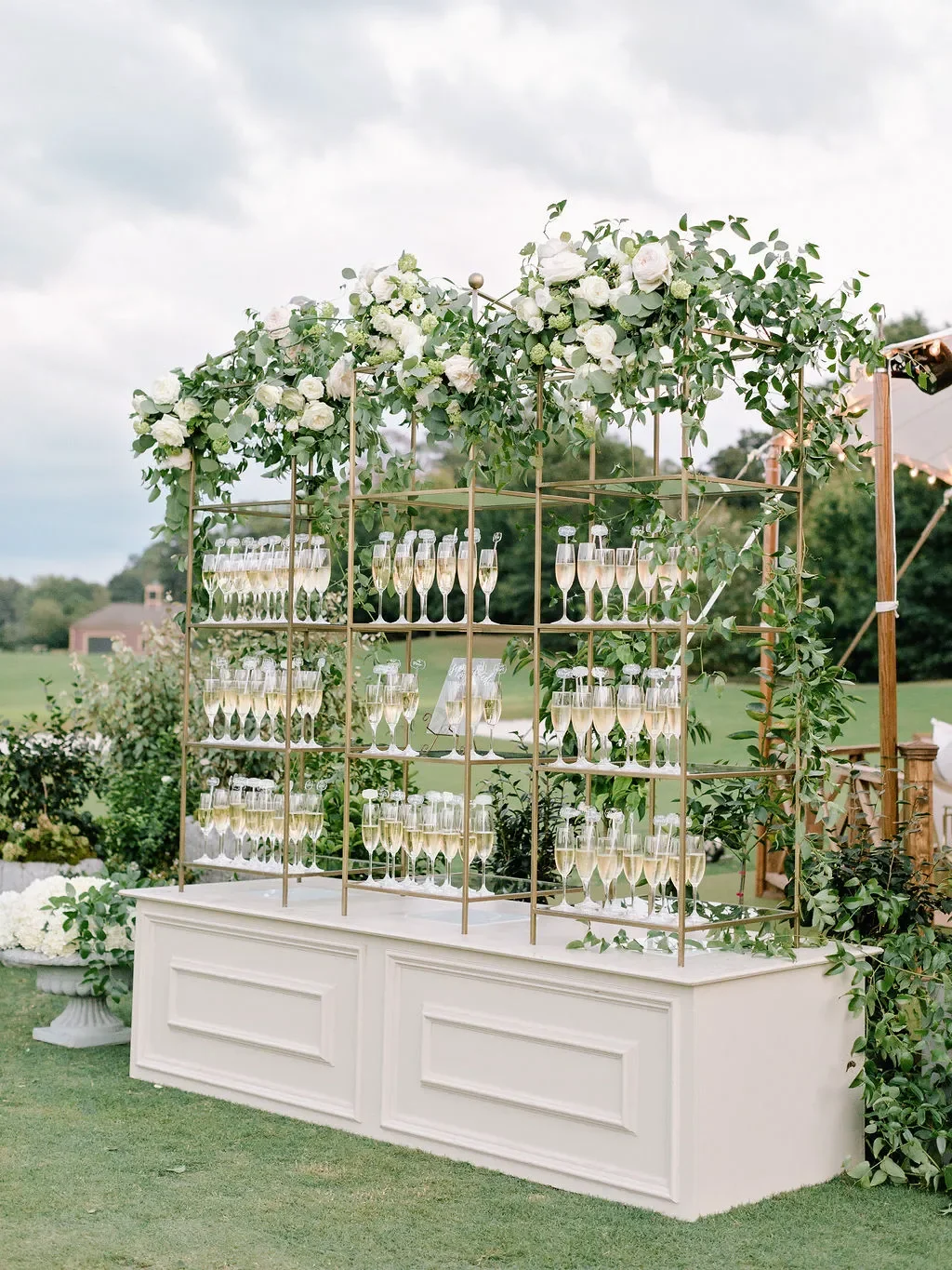 A closer look at the genius detail that made this champagne wall so memorable — each pre-poured flute of sparkling wine held a custom laser-cut acrylic pick with the guest's name and table number written in elegant white calligraphy. Guests simply fo
