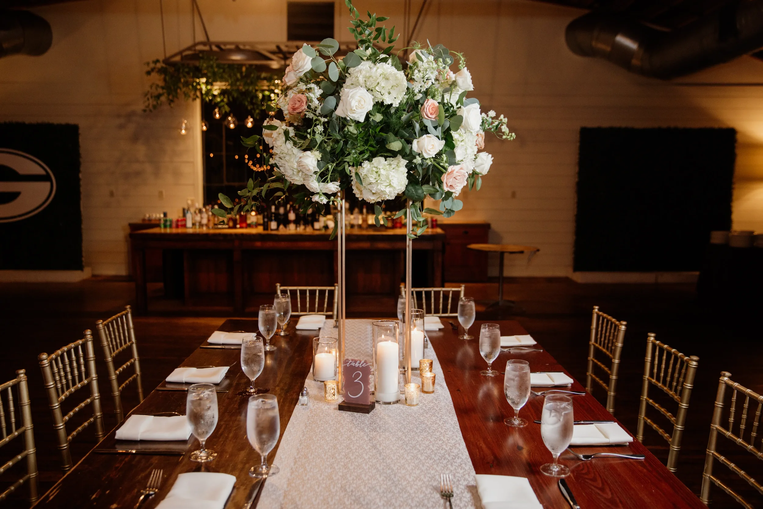 Elegant acrylic table number with white calligraphy script in a warm candlelit setting.