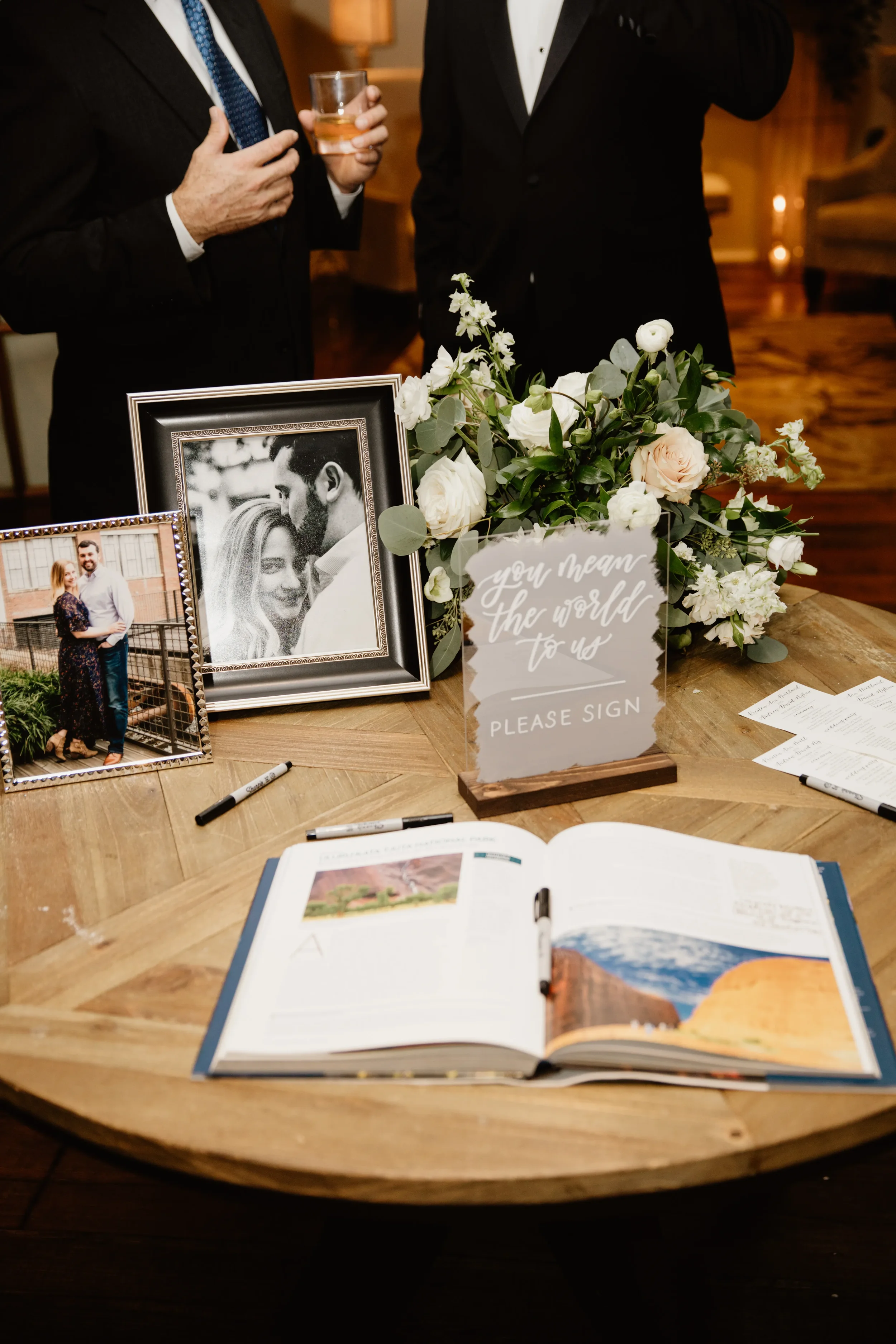 Custom painted-back acrylic wedding guestbook sign with white lettering and a wood stand.