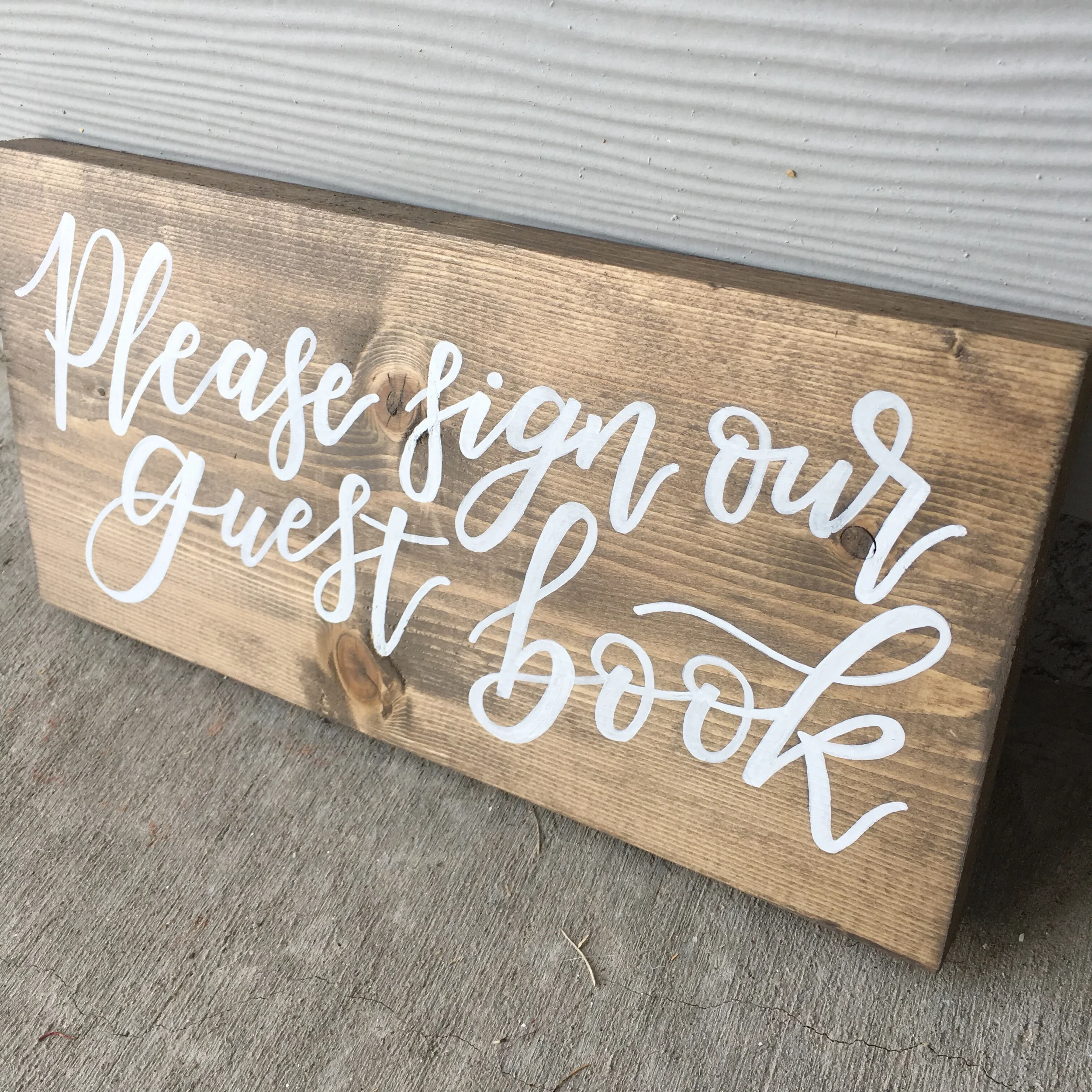 "Please sign out guest book" stained wood sign in white hand-lettering.