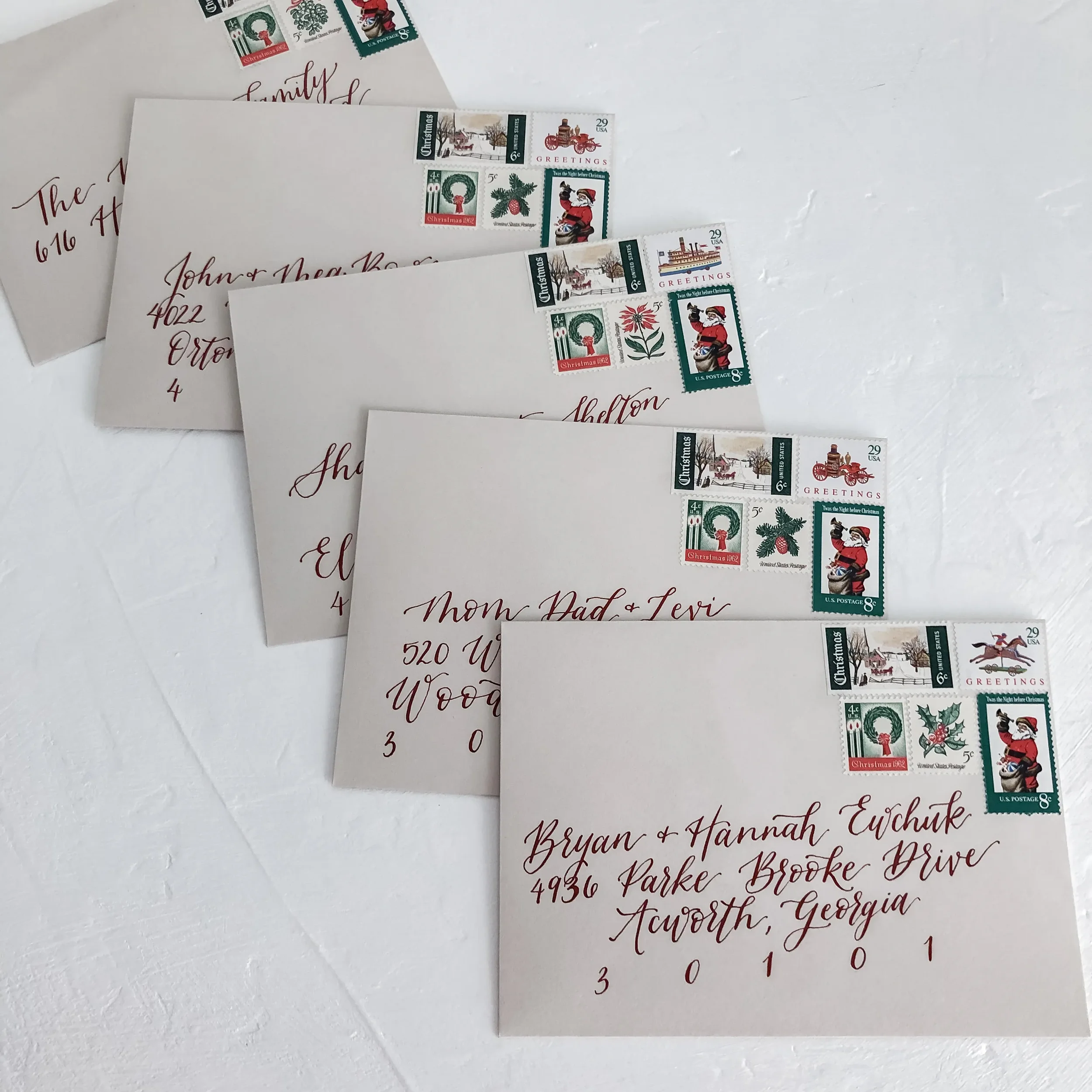 Perfect for a vintage winter celebration, this stack of warm neutral taupe envelopes utilizes rich crimson red ink for guest addressing. Paired with vintage Christmas postage stamps, this design bridges the gap between old-world romance and modern ru