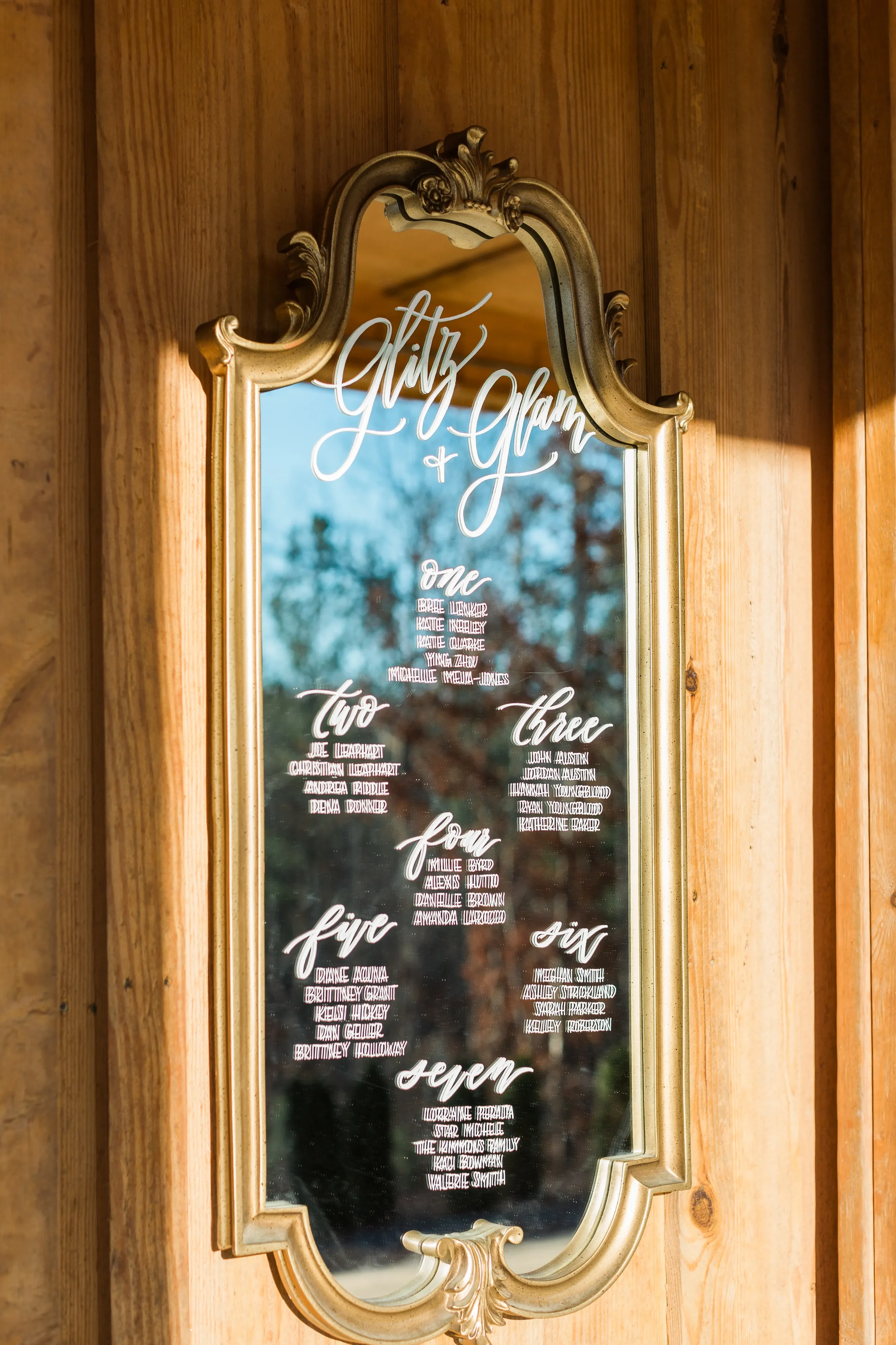 Make finding seats an luxurious experience with a large vintage gold mirror seating chart. Hand-lettered with organized guest table assignments below, this framed glass sign adds timeless elegance and venue reflection to your reception space.