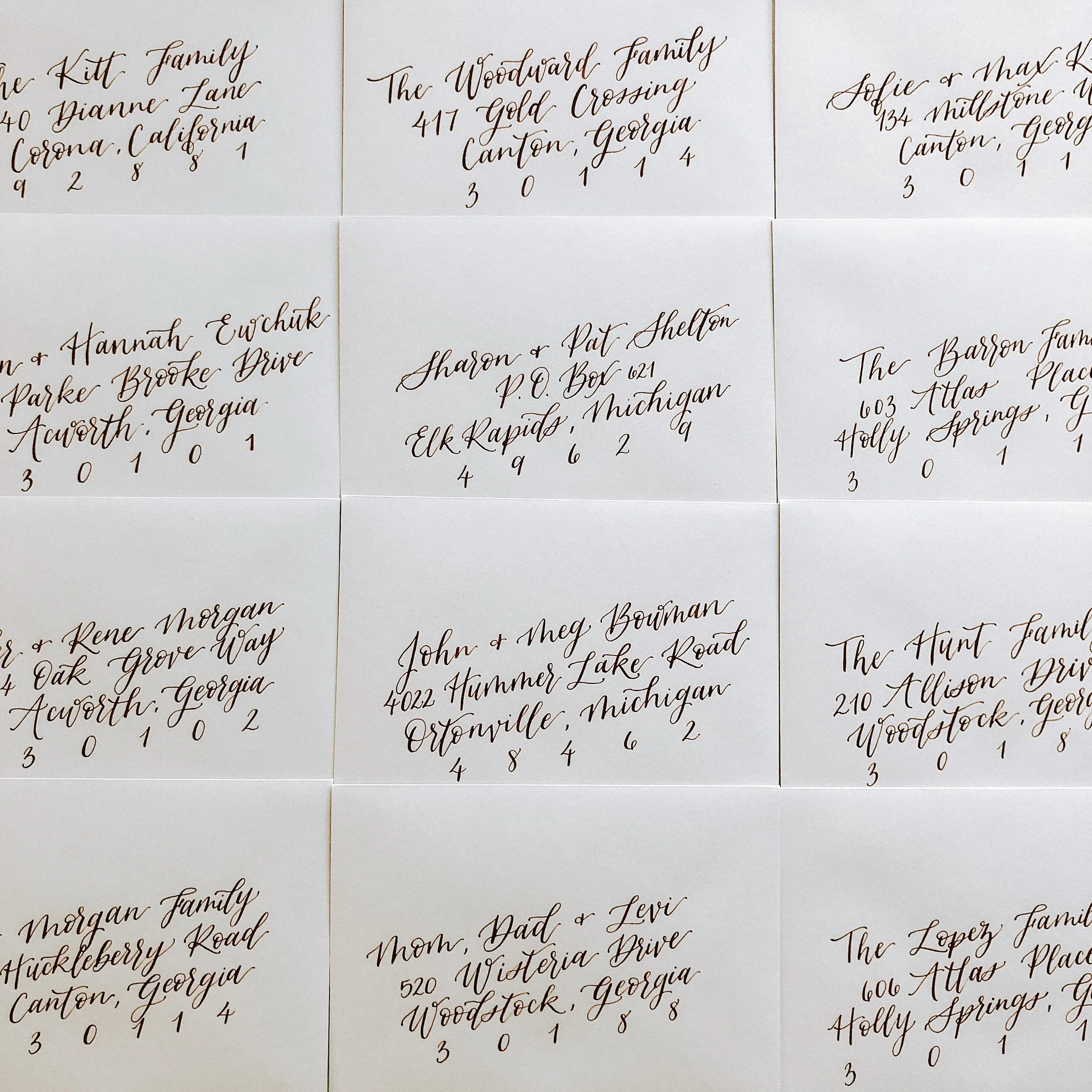 Warm neutral wedding guest envelopes featuring rich burgundy hand-lettering.