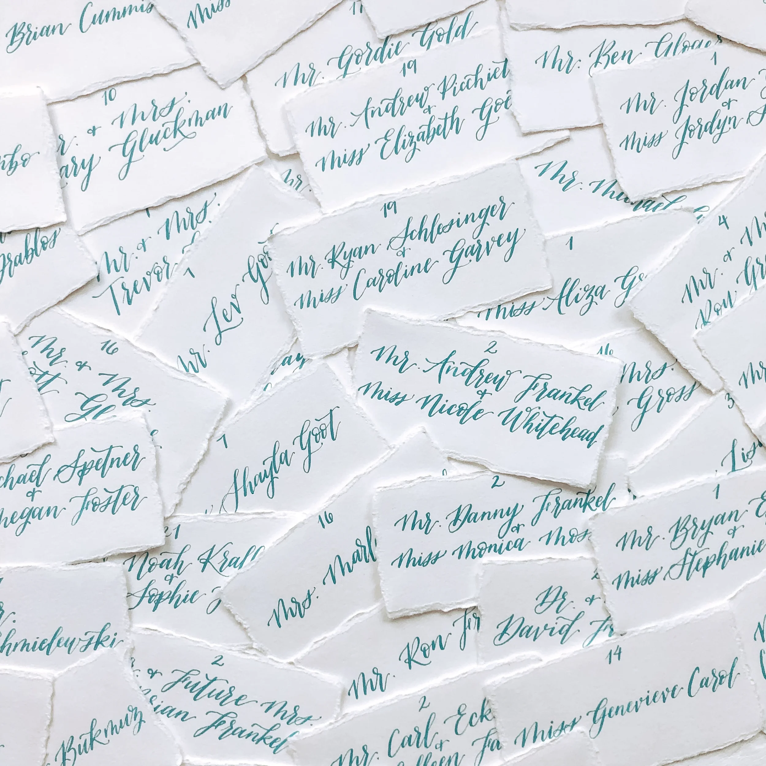 Torn edge paper escort cards with dusty blue calligraphy and table numbers.