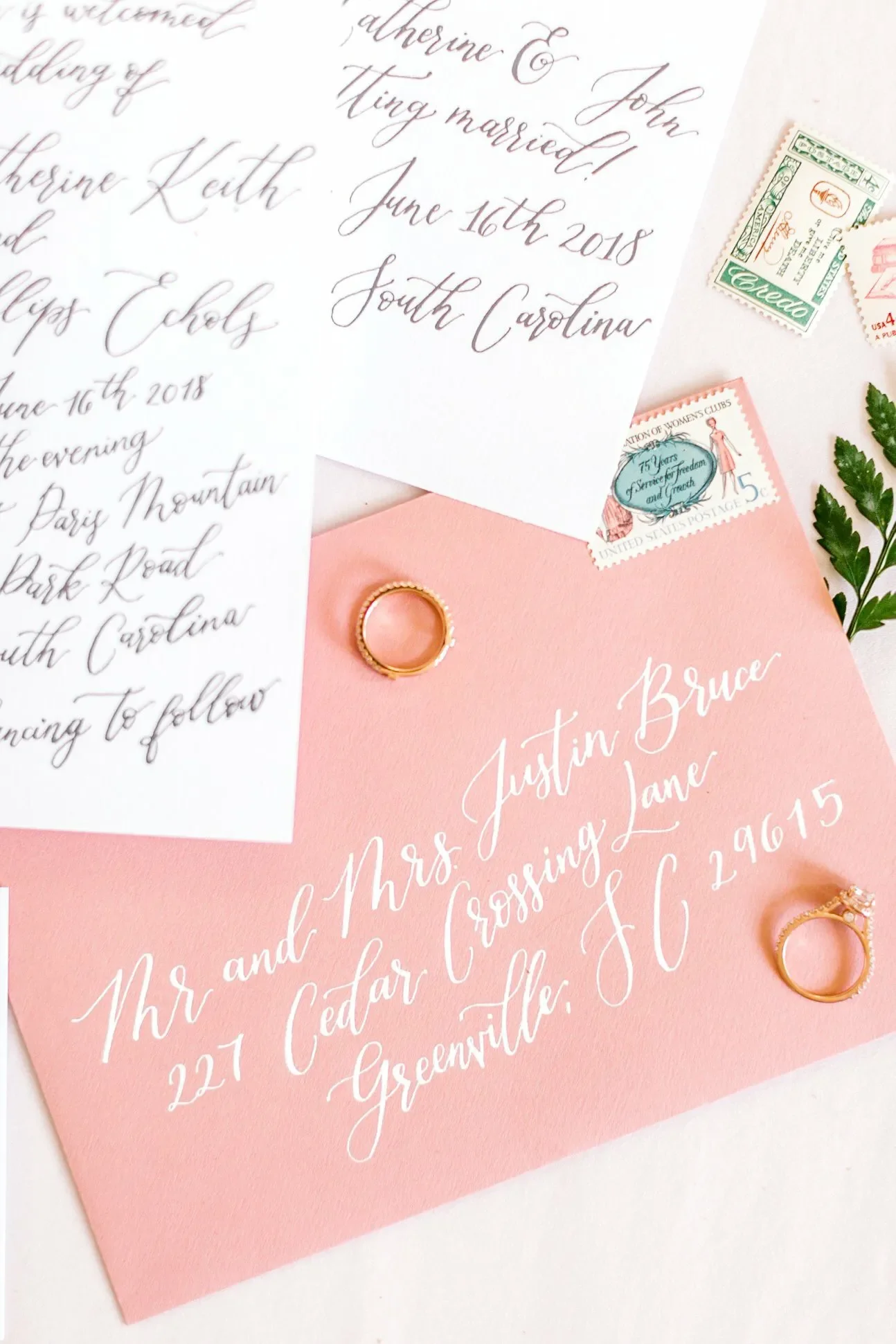 Whimsical peach and coral wedding stationery flat lay featuring elegant cursive script and green ferns.