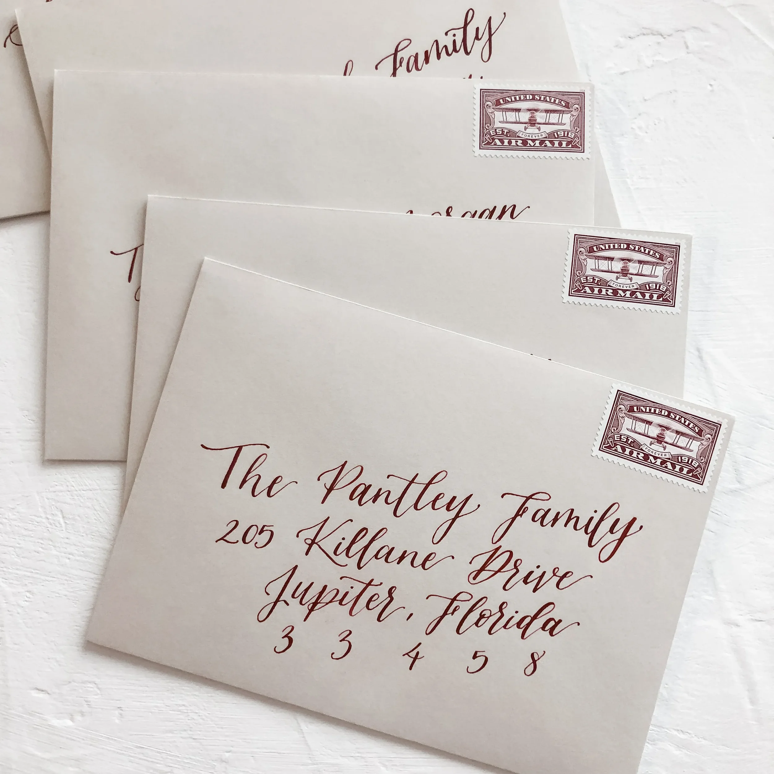 Perfect for an organic autumn or winter celebration, this stack of warm neutral taupe envelopes utilizes rich crimson red ink for guest addressing. Paired with vintage monochromatic postage stamps, this design bridges the gap between old-world romanc