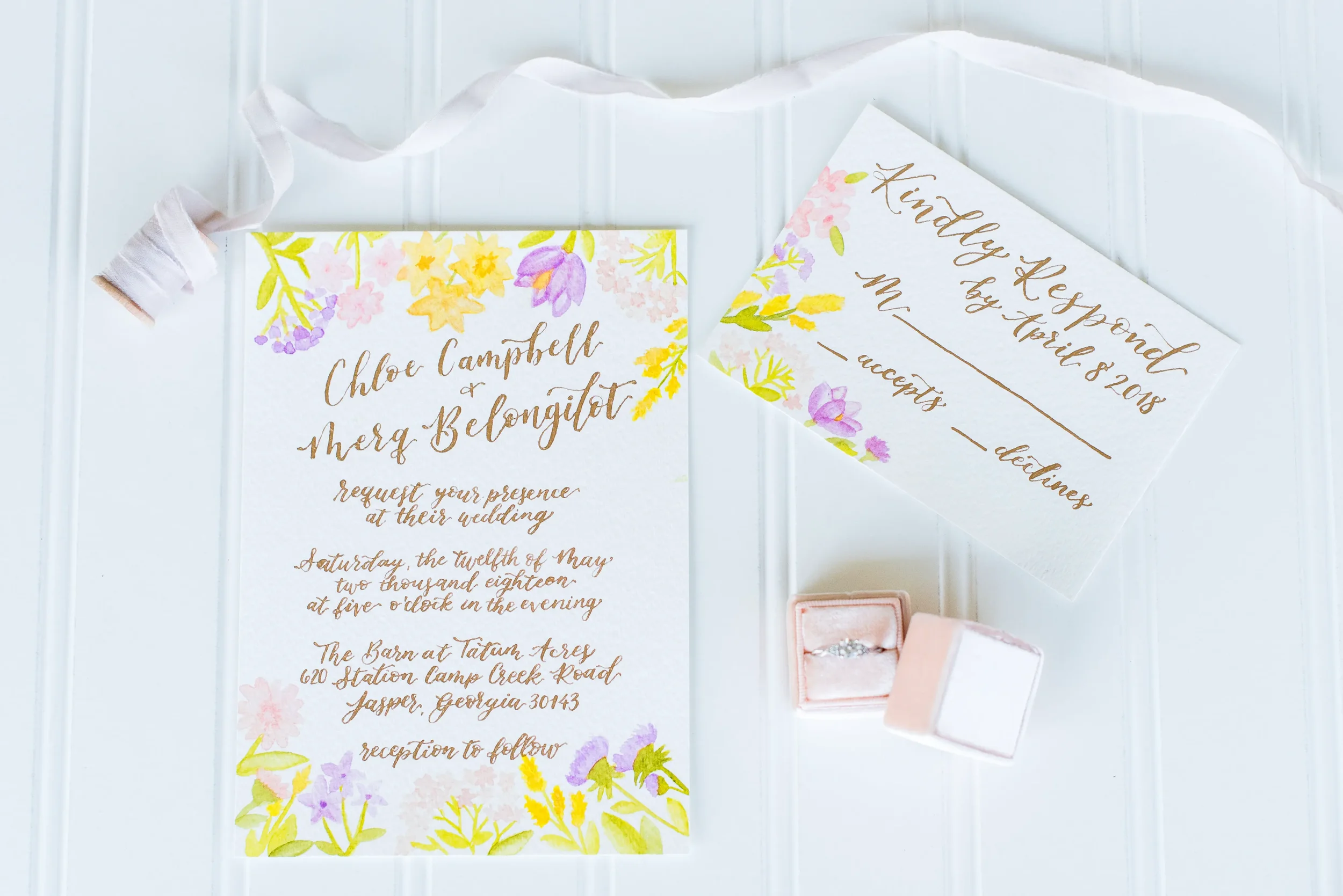 Watercolor wedding invitation suite styled with a pink velvet ring box, vintage stamps, and silk ribbon.