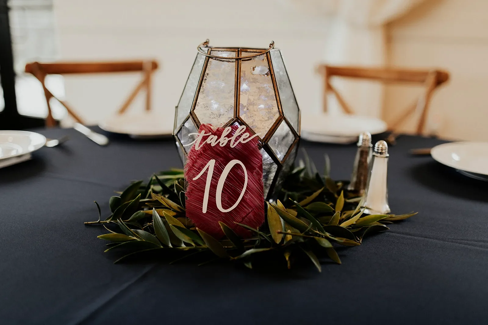 Capture the fine details of your reception with elegant acrylic table number signs. The rich, hand-painted burgundy backing provides a high-contrast canvas for white calligraphy script, reflecting beautifully alongside textured gold mercury glass can