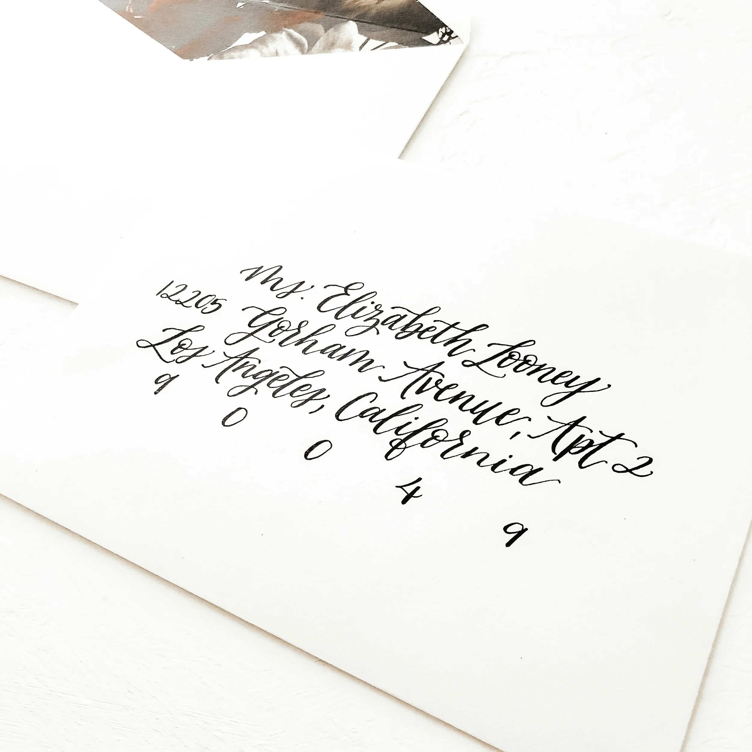Give your traditional stationery an artistic rewrite with a surprise interior reveal. This elegant off-white guest envelope uses classic, sweeping black ink cursive for the exterior addressing, while the interior opens up to a stunning, deep-toned mo