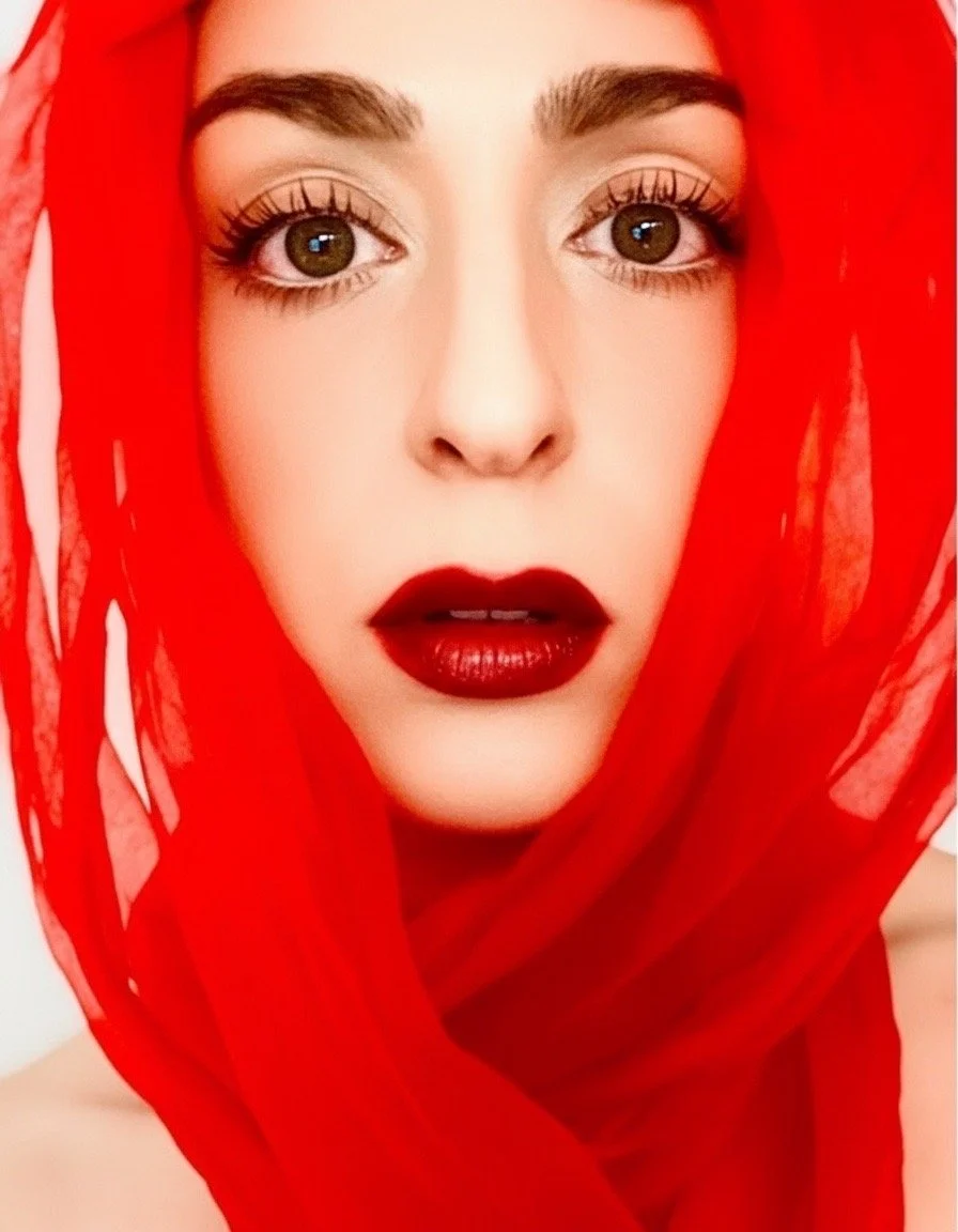 Kate Bailey is in a red translucent scarf looking at the camera. It has a high fashion editorial feel.