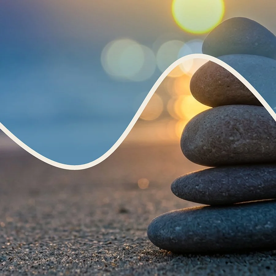 Stacked smooth stones on a sandy surface with a sunset and bokeh lights in the background, and a white wave overlay.