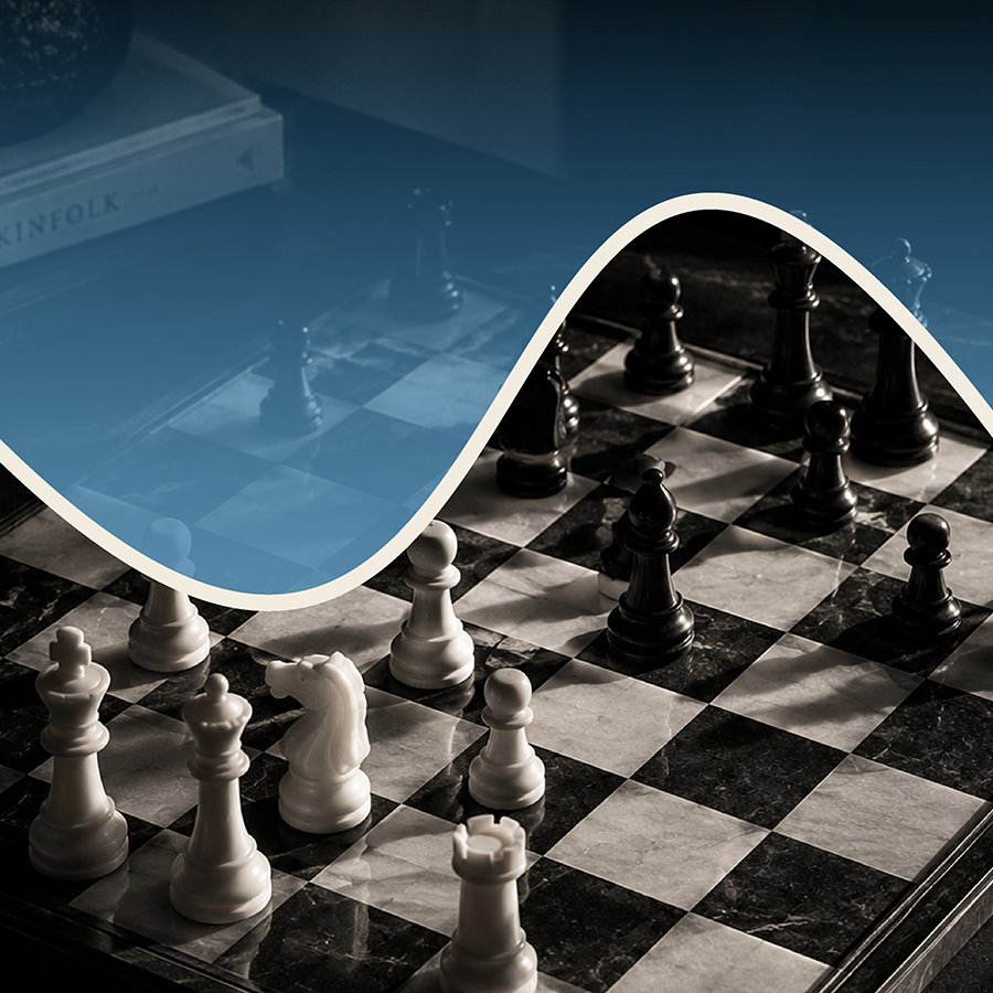 Chessboard with black and white pieces, partially covered by a blue sheet of paper.