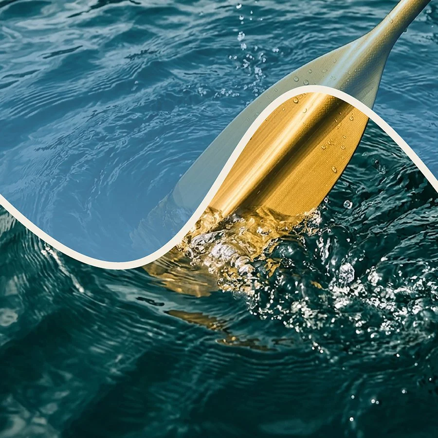 Close-up of a golden oar or paddle in the water with ripples and splashes.