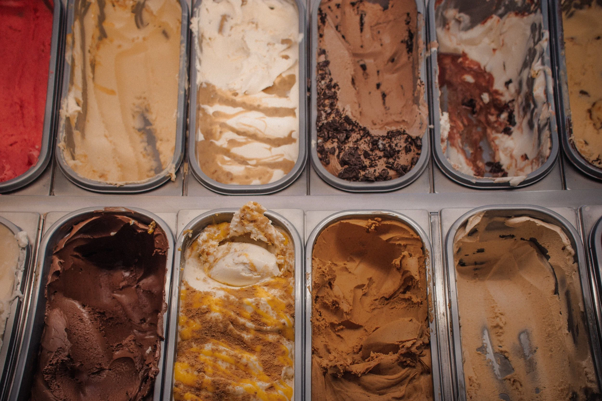 Several trays of different flavors of ice cream in a display case.