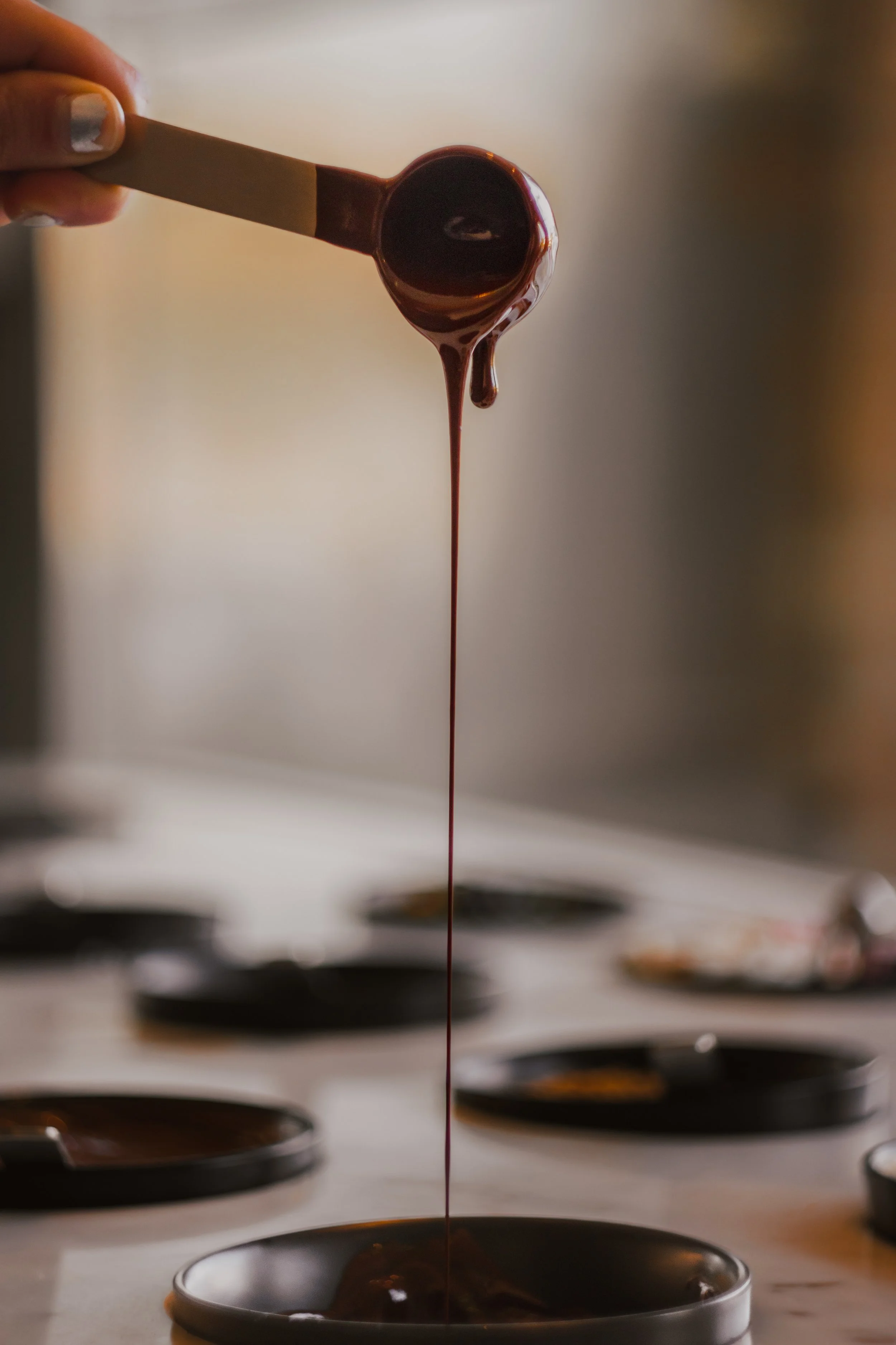 Chocolate being poured into metal molds on a marble surface.