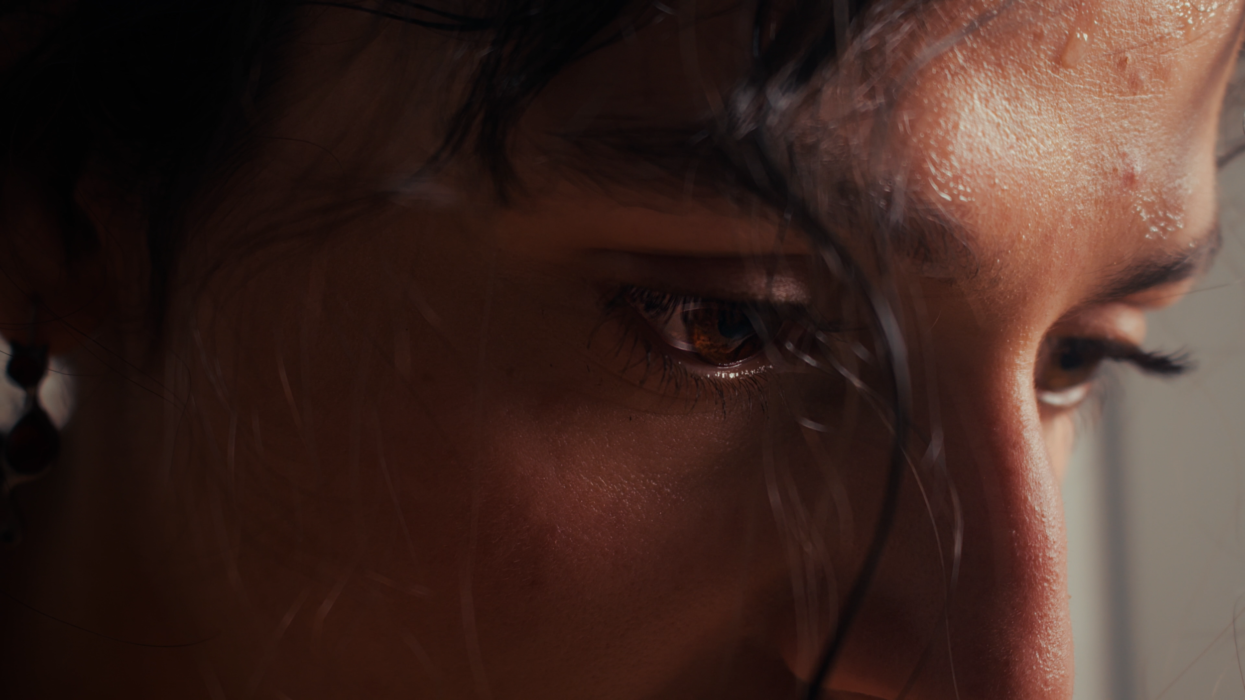 Close-up of a person's face, focusing on the right eye and cheek, with wet skin and dark hair partially covering the face.