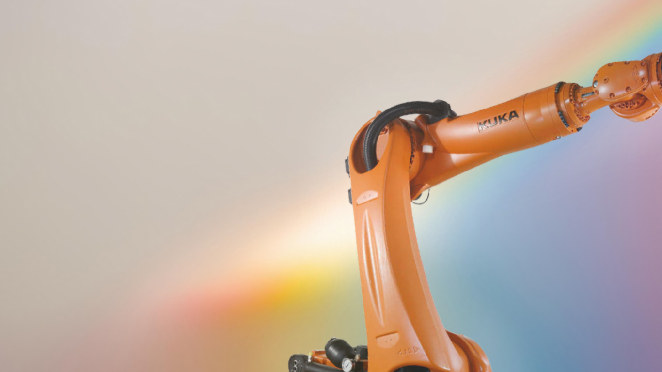 Close-up of an orange KUKA robotic arm against a rainbow-colored background.