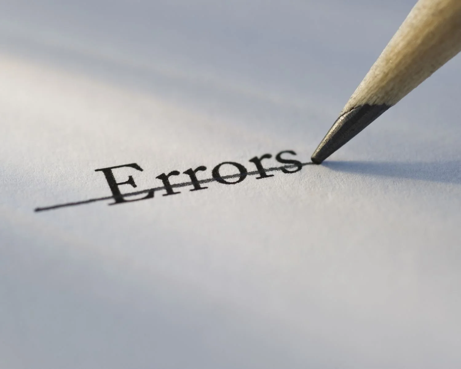 A close-up of a pen crossing out the word 'Errors' on a piece of paper.