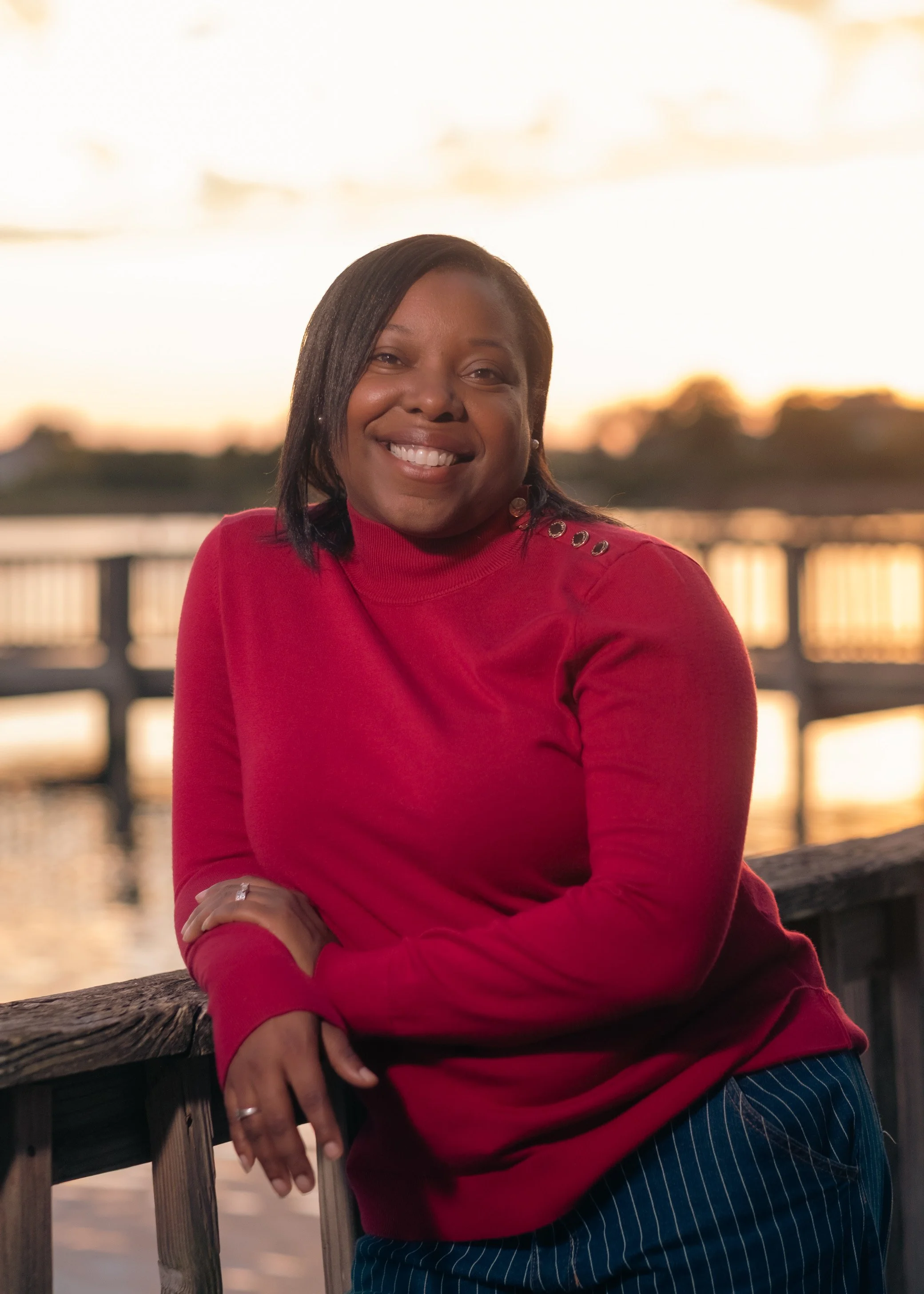 Woman smiling red shirt sunset waterfront arms crossed