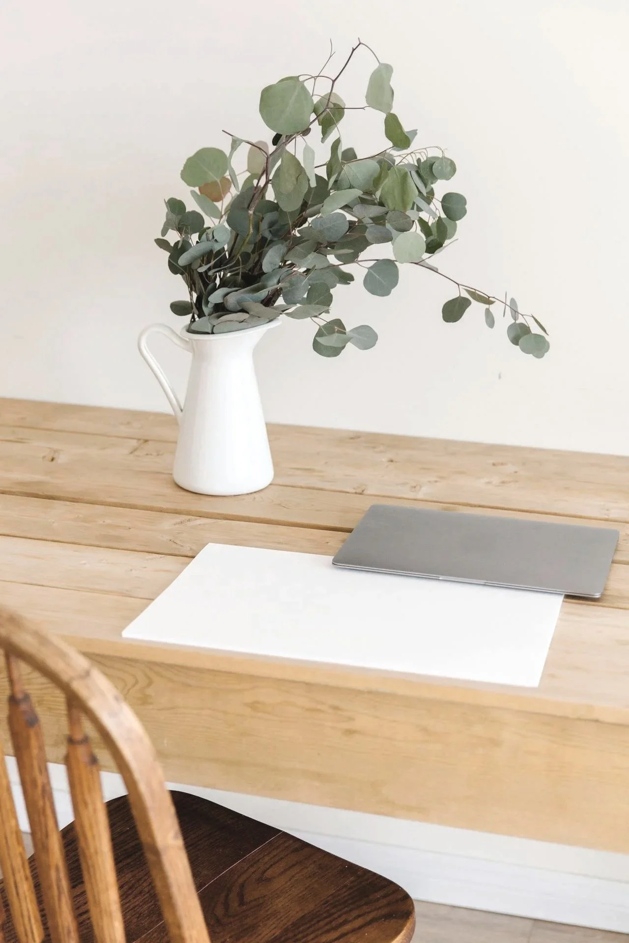 Minimalist desk with a vase of eucalyptus and a laptop, reflecting a welcoming and professional healthcare practice.