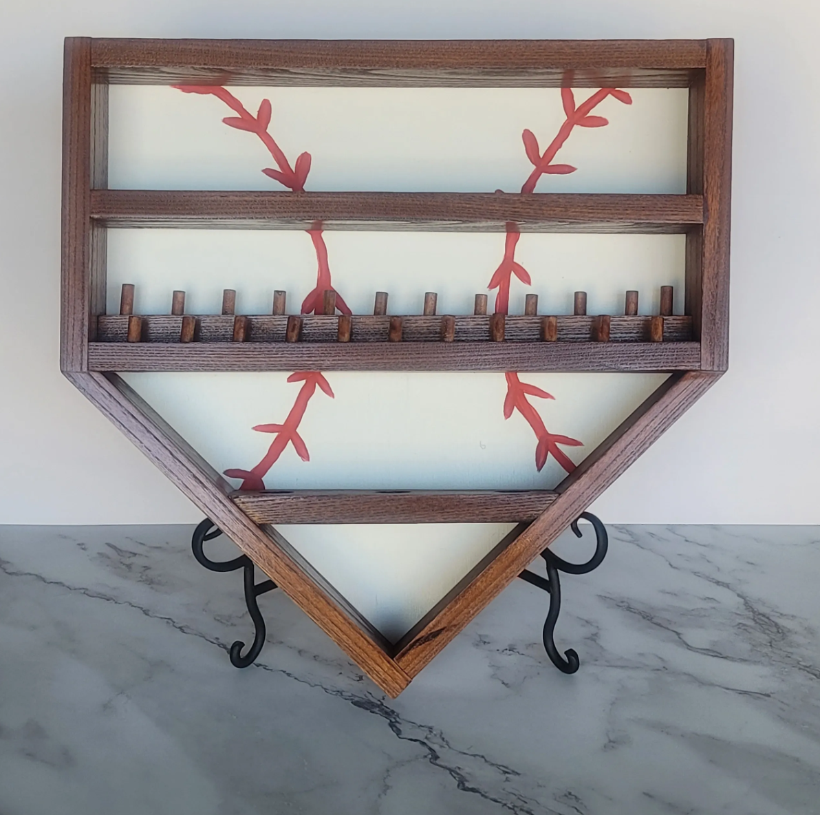Decorative wall hanging of a wooden barn wood frame with a glass panel, painted with red vine-like branches, mounted on a white wall with black metal scroll brackets.
