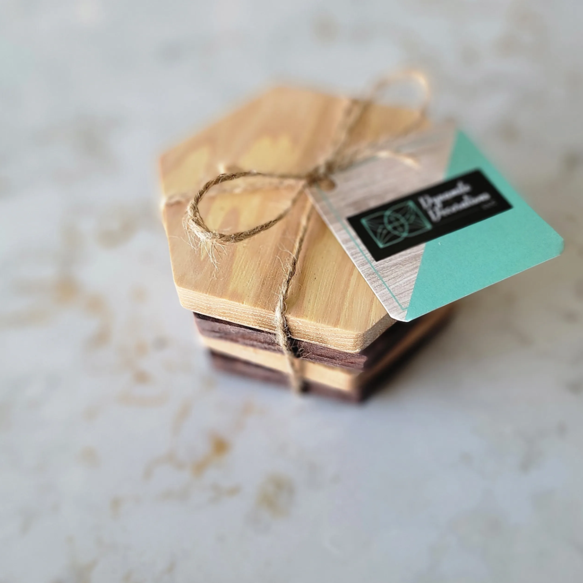 Stacked wooden coasters bundled with twine and a black and teal tag.