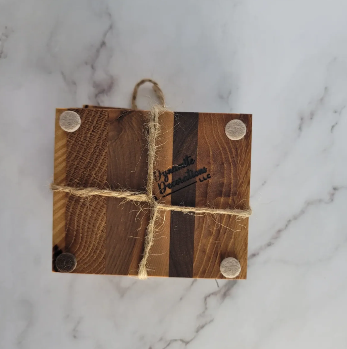 Small wooden box wrapped with twine, bearing four felt pads on each corner, on a marble surface.