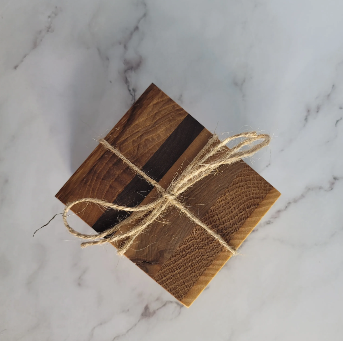 A small wooden box tied with a piece of jute twine, placed on a white marble surface.