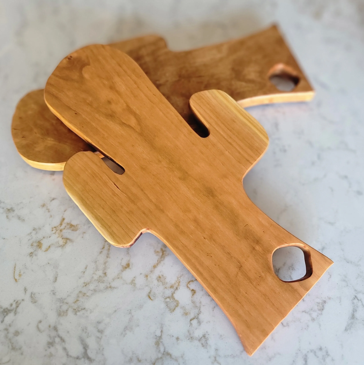 Two wooden cutouts with rounded edges and hole openings, lying on a light-colored surface.