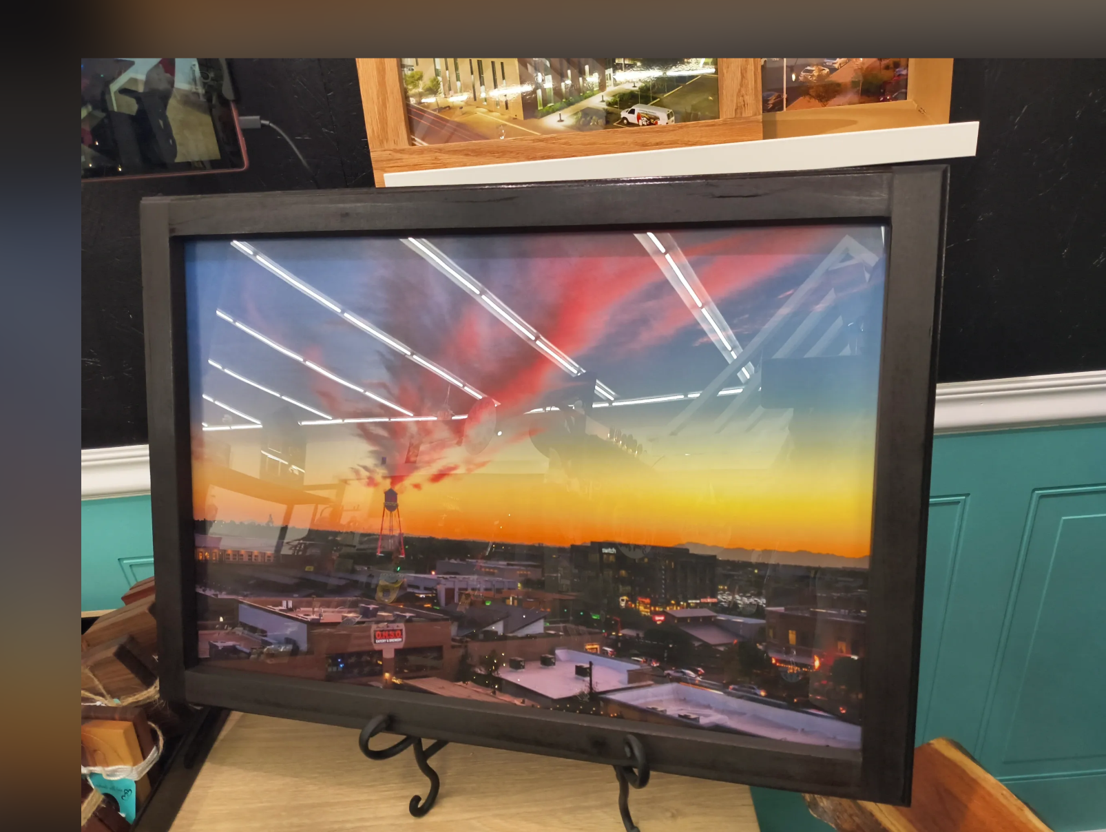Display monitor showing a cityscape with a sunset and an industrial chimney emitting smoke, reflected with reflections of ceiling lights.