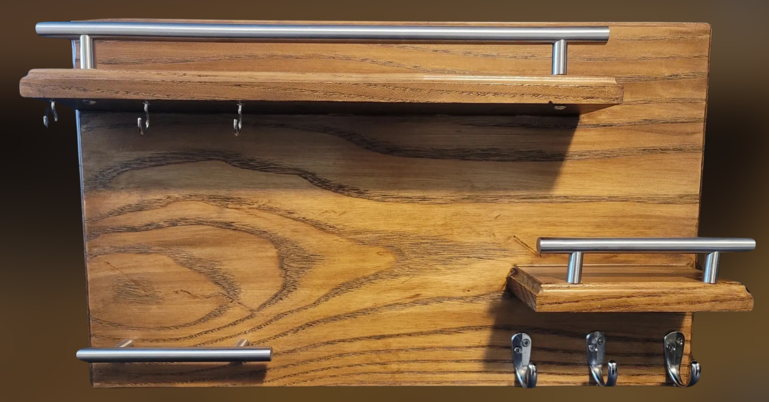 Wooden wall organizer with metal hooks and rails, featuring three horizontal hooks at the bottom and two smaller hooks at the upper part.