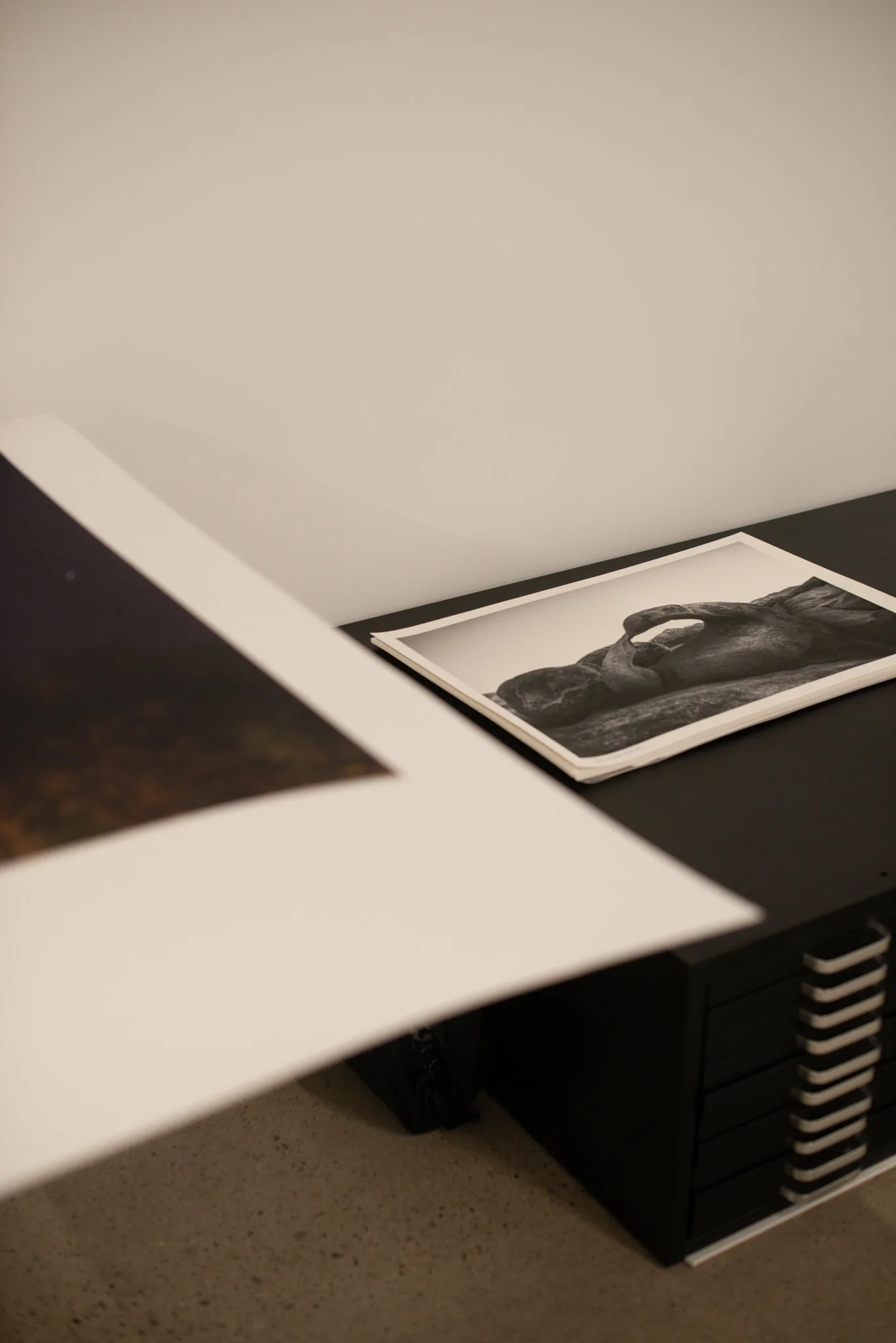 A black and white print of a sculpture of a human head placed on a table or desk.
