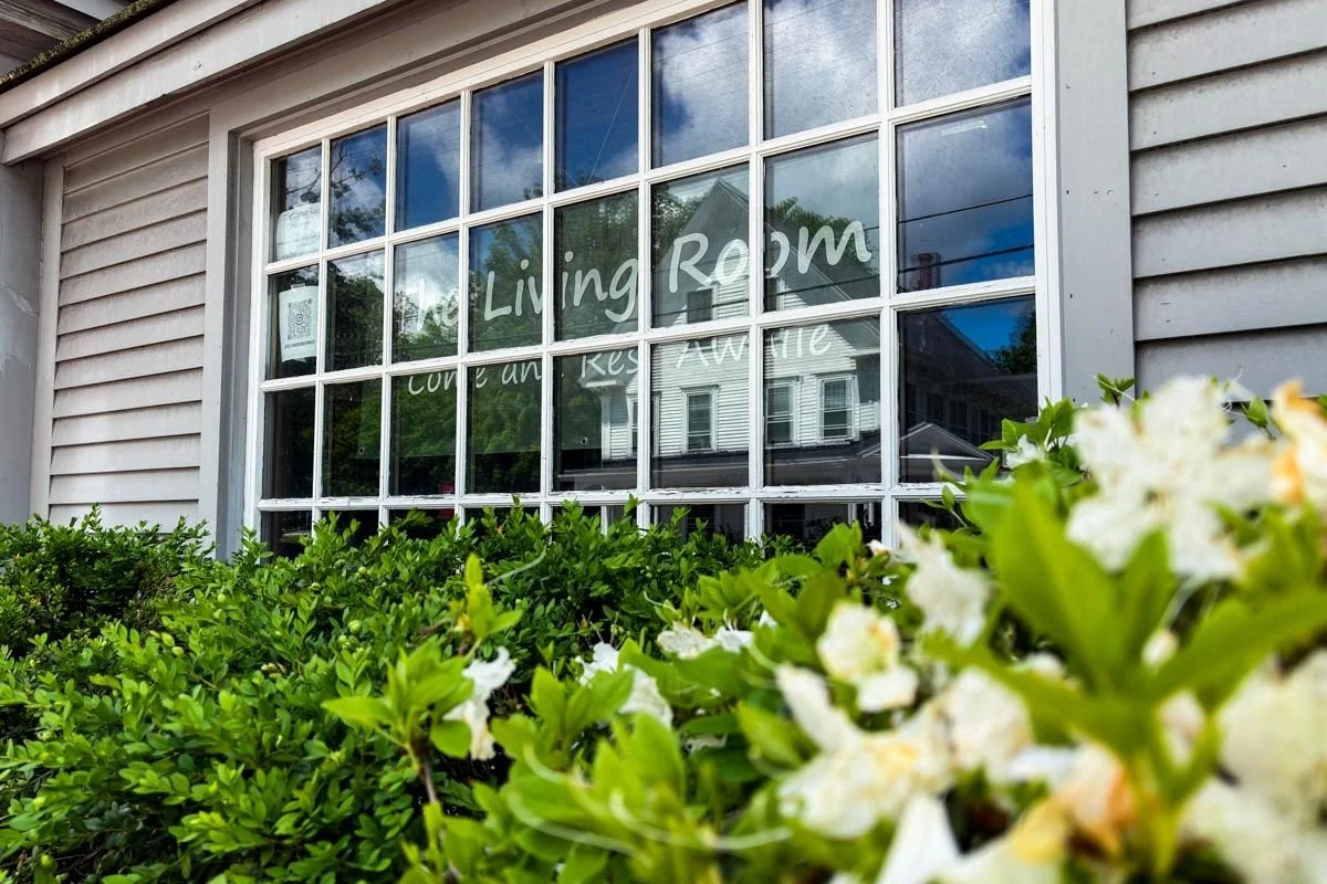 The Living Room storefront window in Henniker, NH, with flowering shrubs in front