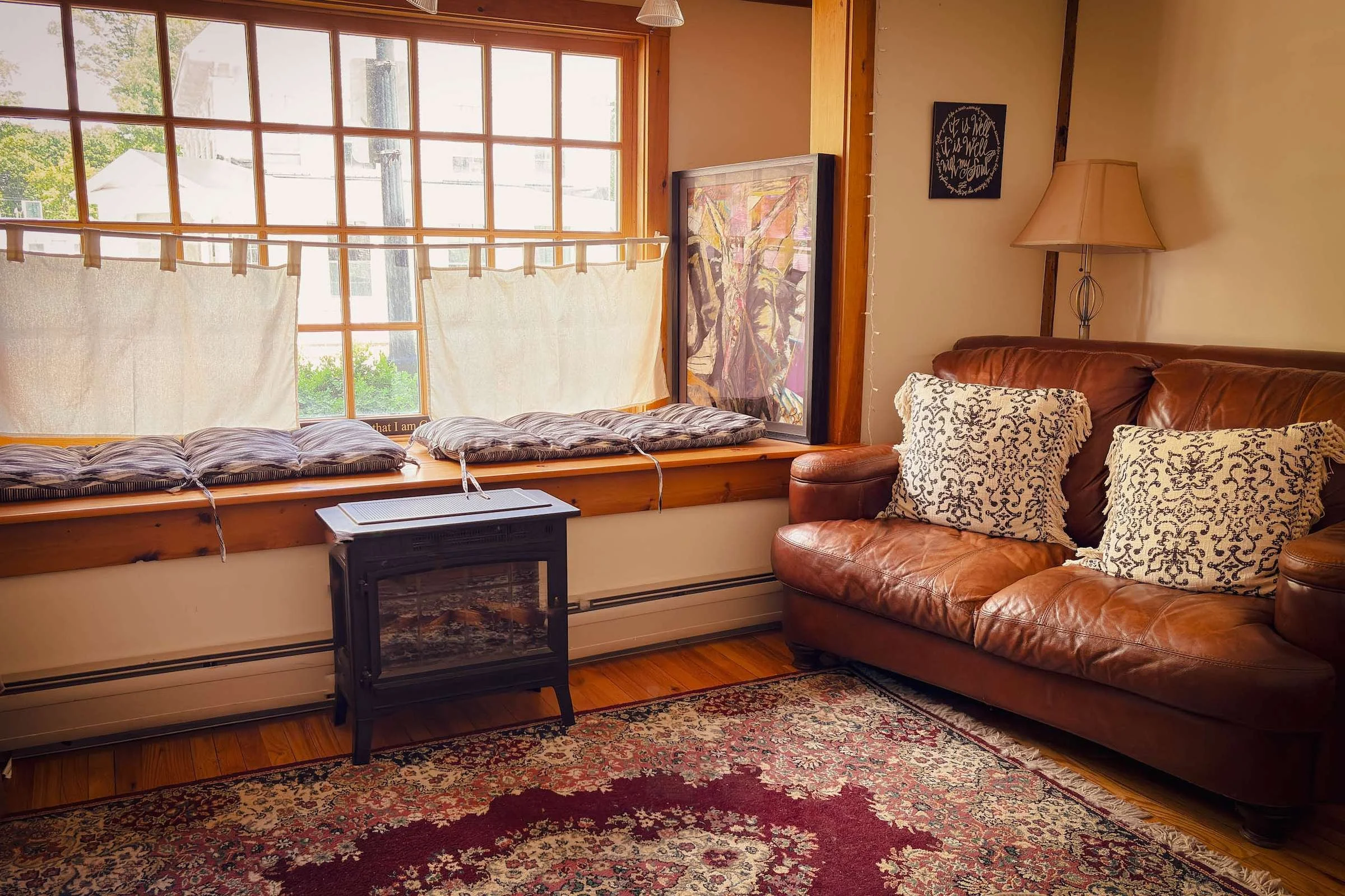 Window seat with striped cushions and leather couch in The Living Room, a Christian prayer space in Henniker, NH