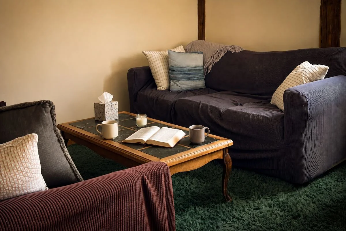 Spiritual counseling space at The Living Room, with two mugs and an open Bible on a coffee table