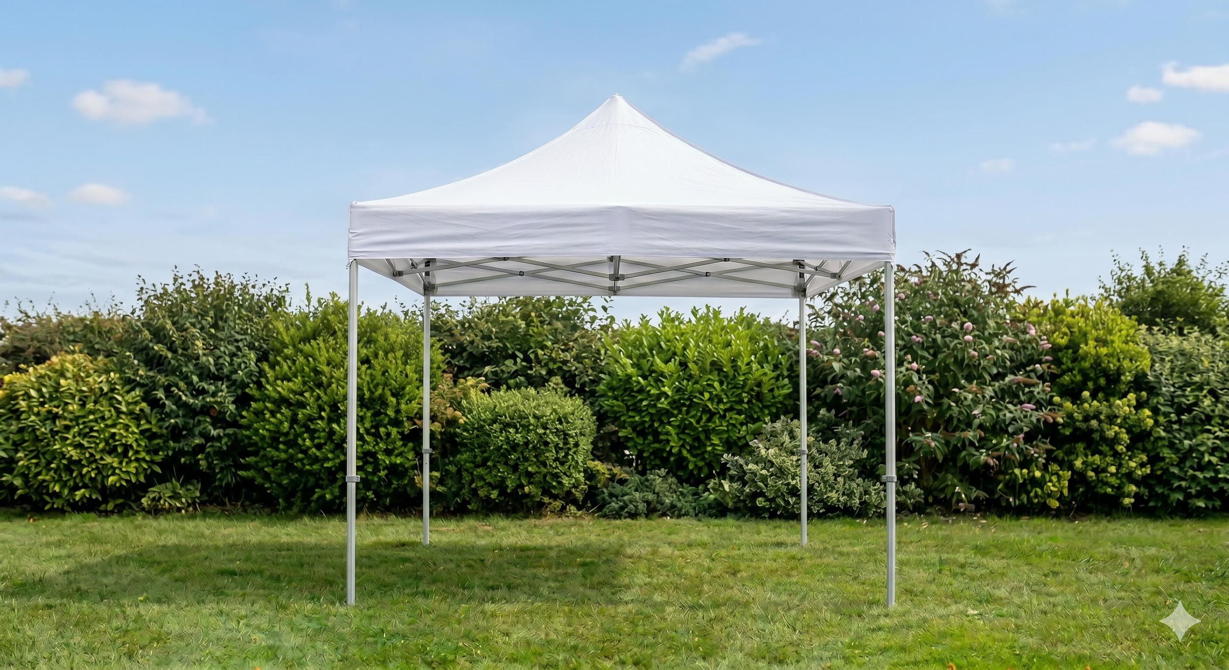 White canopy tent set up on a grassy lawn with bushes and shrubs in the background, under a partly cloudy sky.