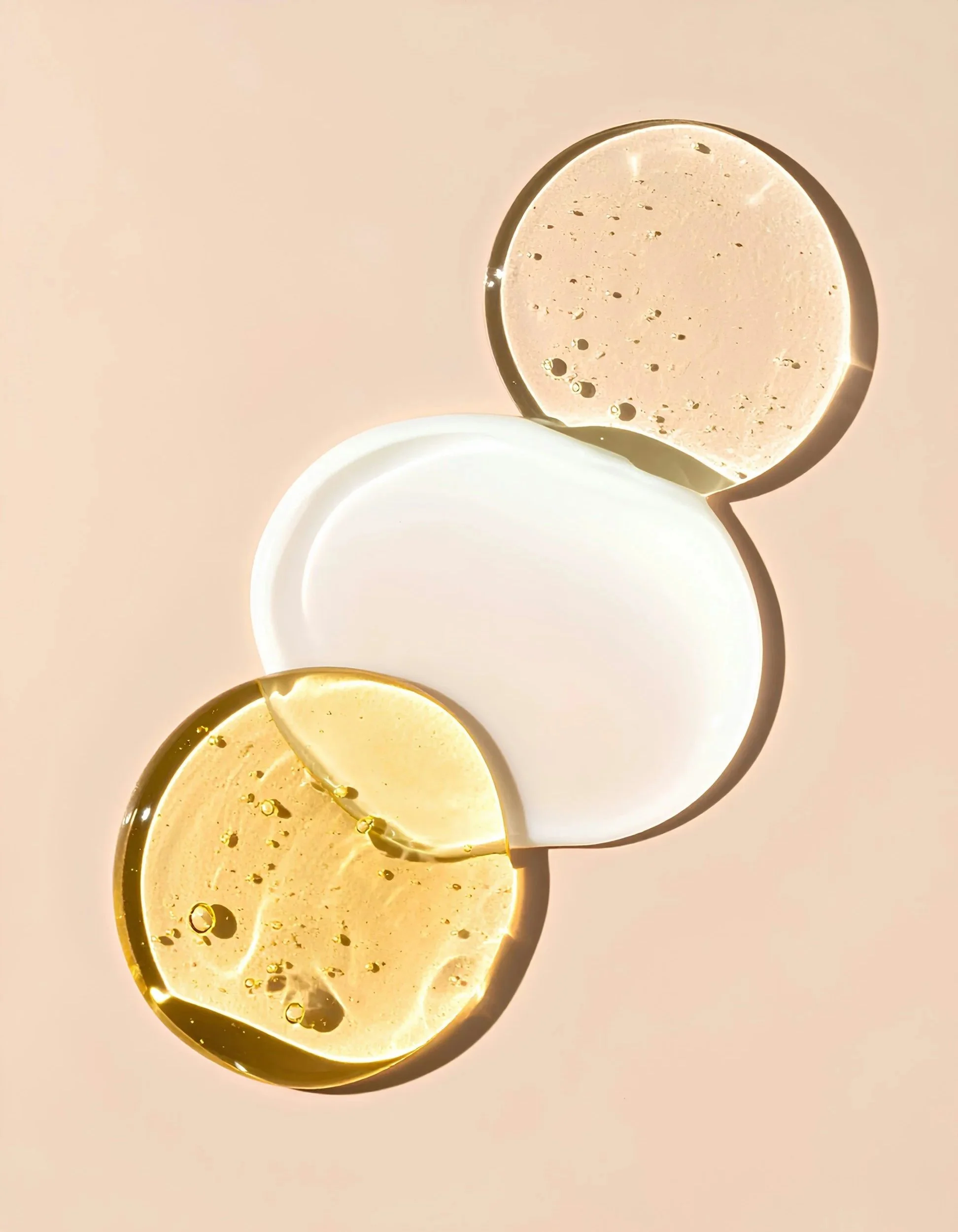 Close-up of three circular lamps with different colors and textures, illuminated and casting shadows on a light pink background.