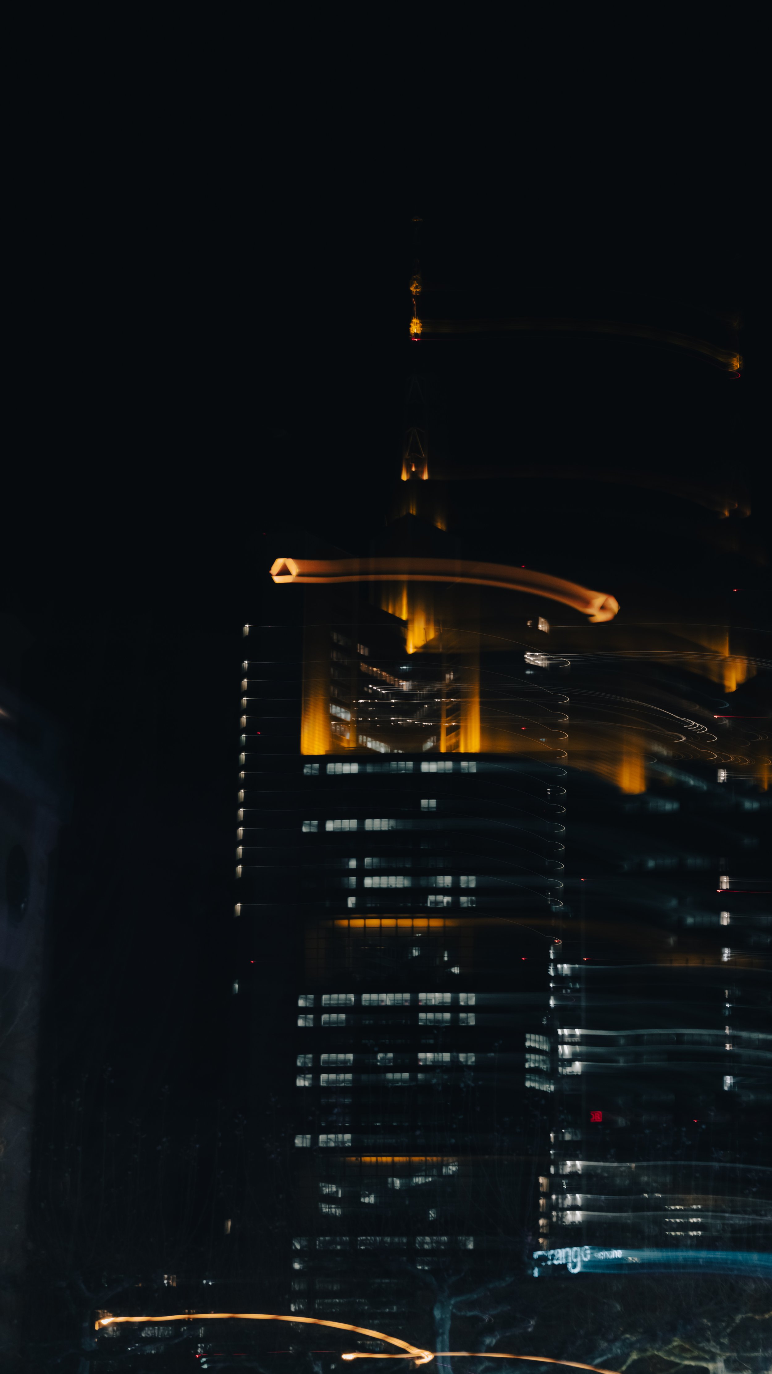 Ein beleuchteter Wolkenkratzer der Commerzbank in Frankfurt bei Nacht mit gelben und weißen Lichtern, teilweise verschwommen durch Bewegung