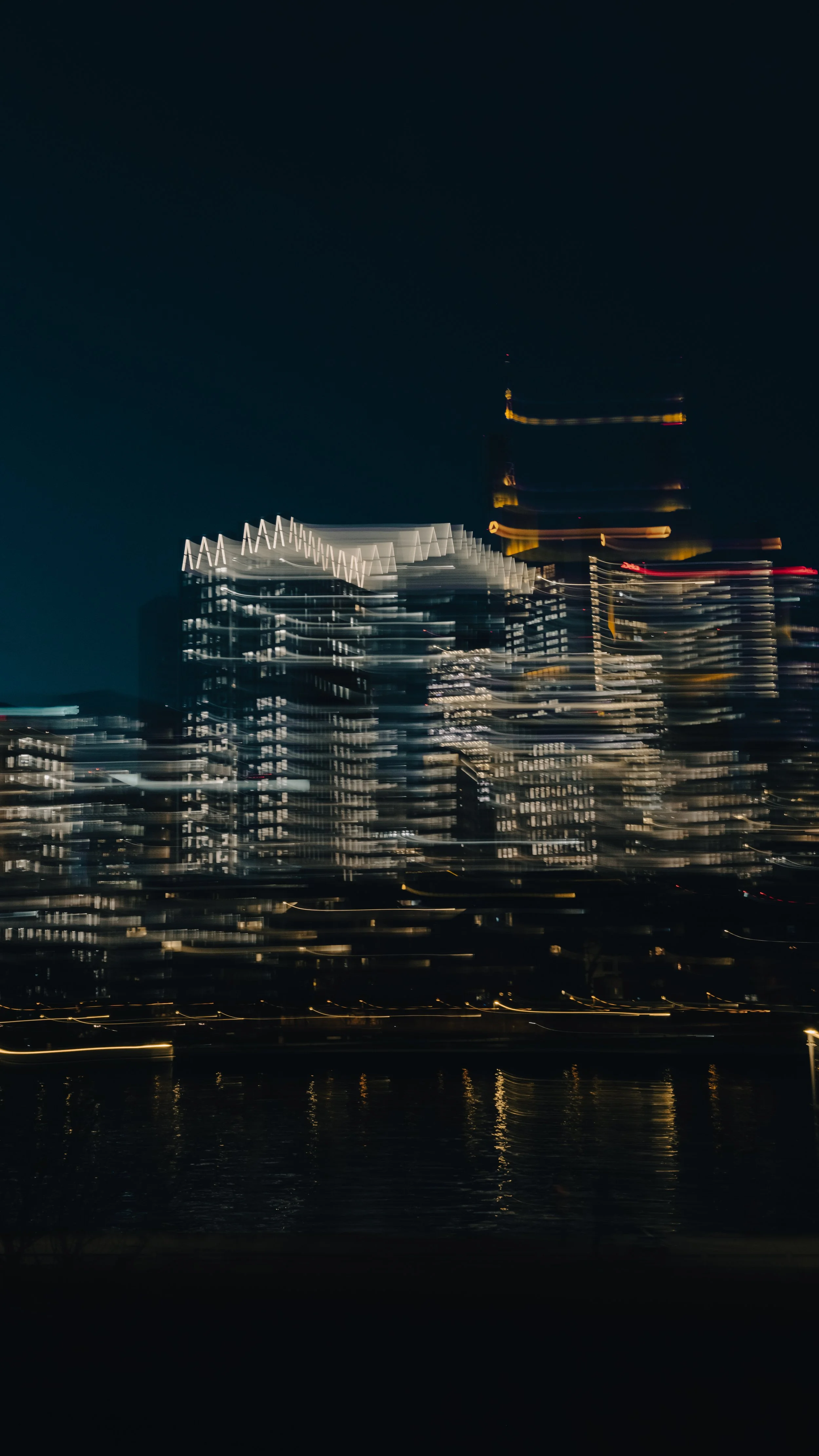 Städtisches Hochhaus in Frankfurt am Main bei Nacht mit Lichter, die sich durch Bewegungsunschärfe verzerrt darstellen.