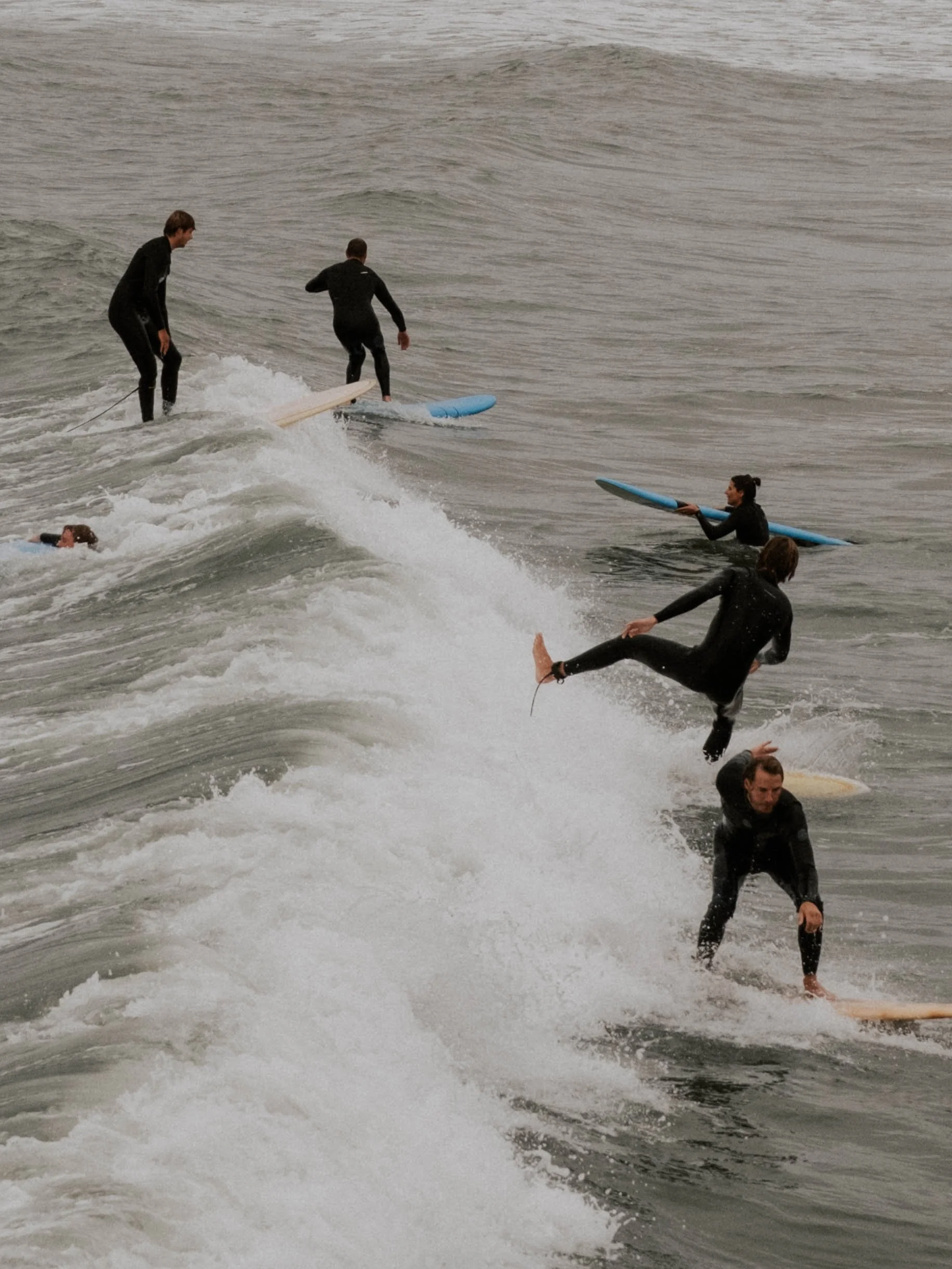 Menschen beim Surfen im Wasser, einige fallen ins Wasser, andere stehen auf Surfbrettern in Den Haag, Niederlande.