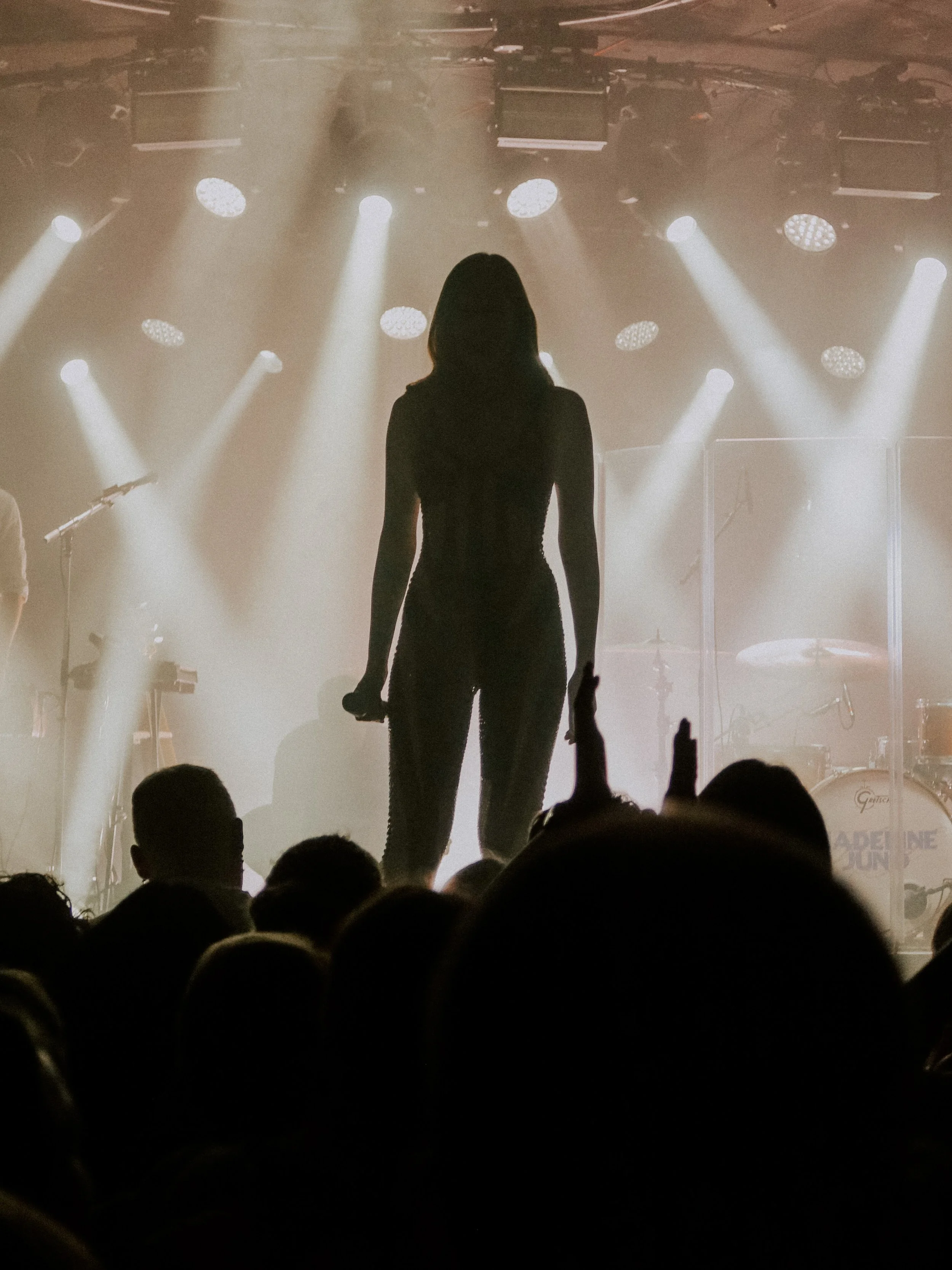 Silhouette einer Frau auf einer Bühne vor hellem Scheinwerferlicht vor einem Publikum bei einem Konzert oder einer Aufführung. Event-Fotografie im Zoom, Frankfurt.