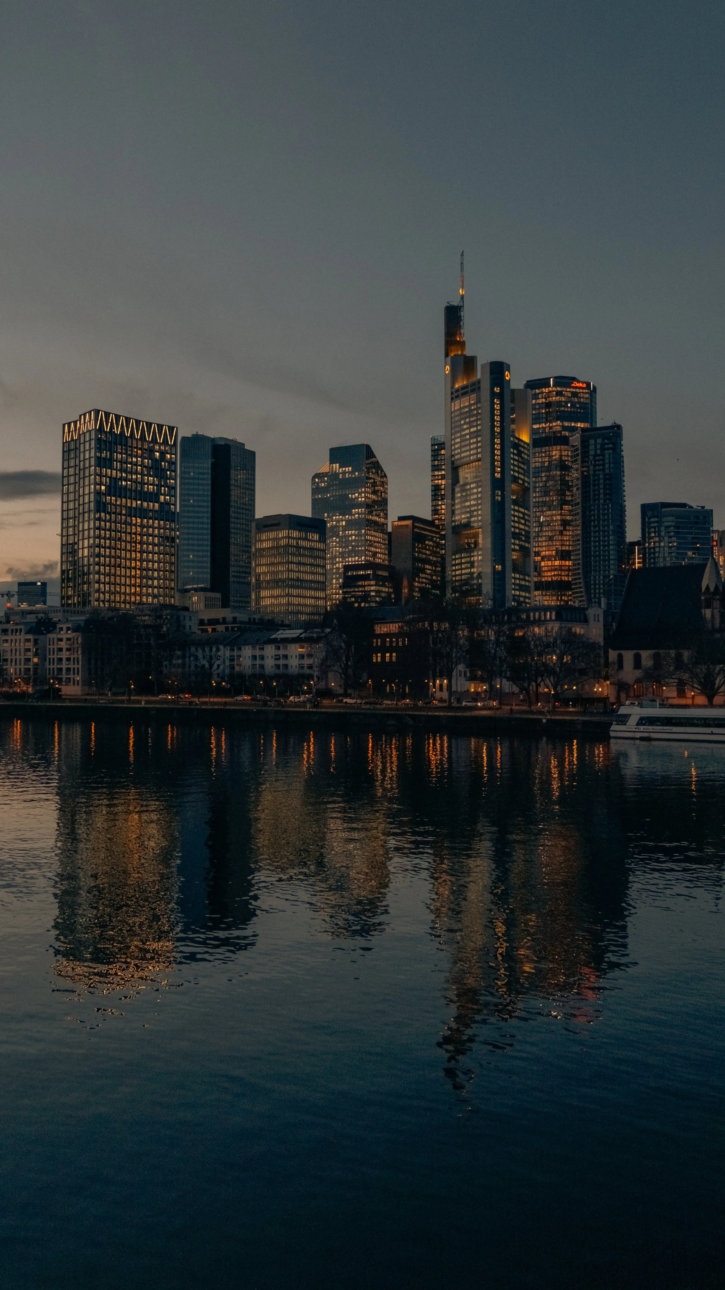 Stadt Skyline von Frankfurt am Main bei Sonnenuntergang mit reflektierenden Gebäuden im Wasser.