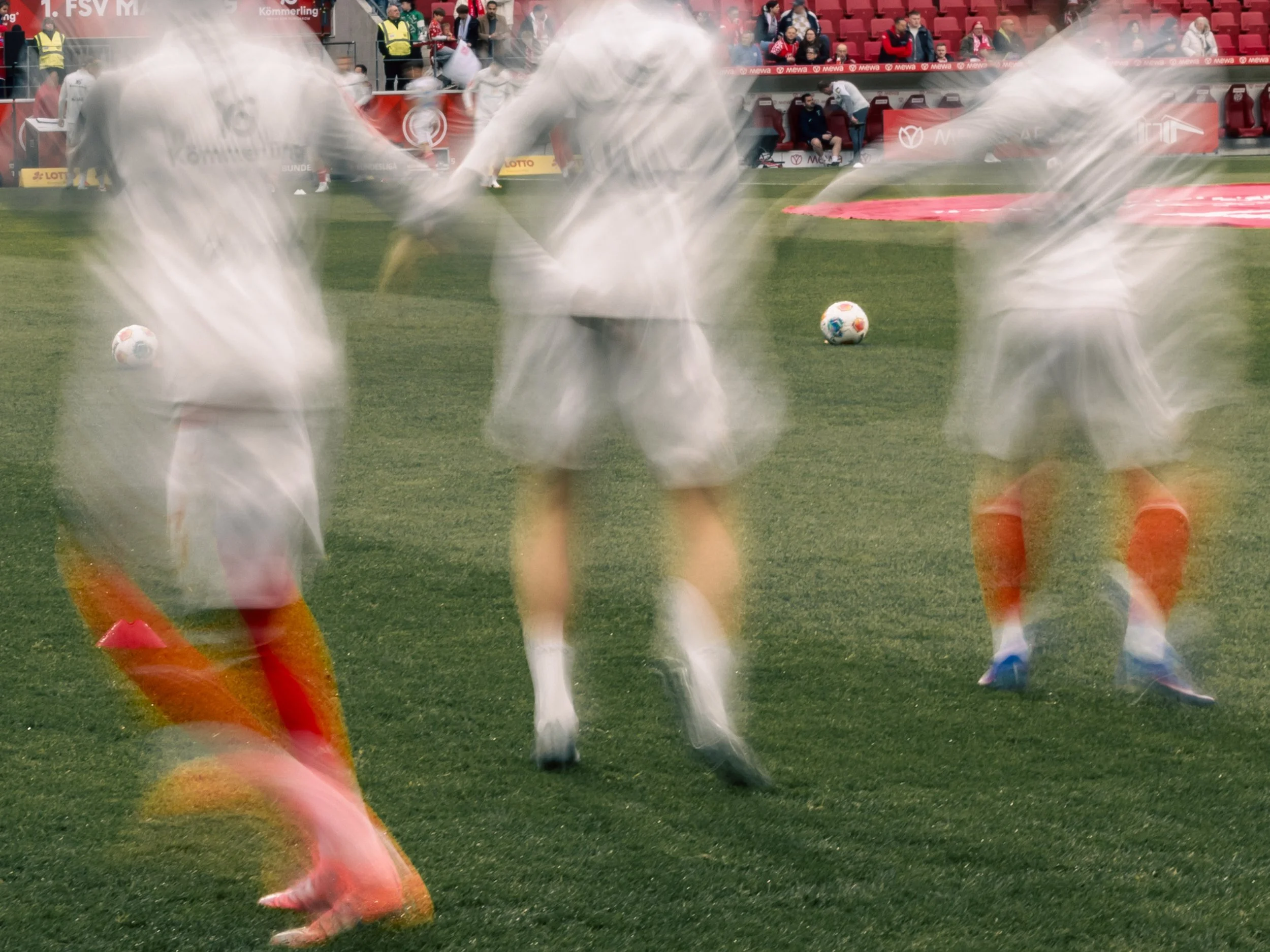 Fußballspieler des 1. FSV Mainz 05 beim Warmmachen auf dem Spielfeld. Verschwommene Bewegungen durch Langzeitbelichtung. Sportfotografie beim Fußball, Bundesliga.