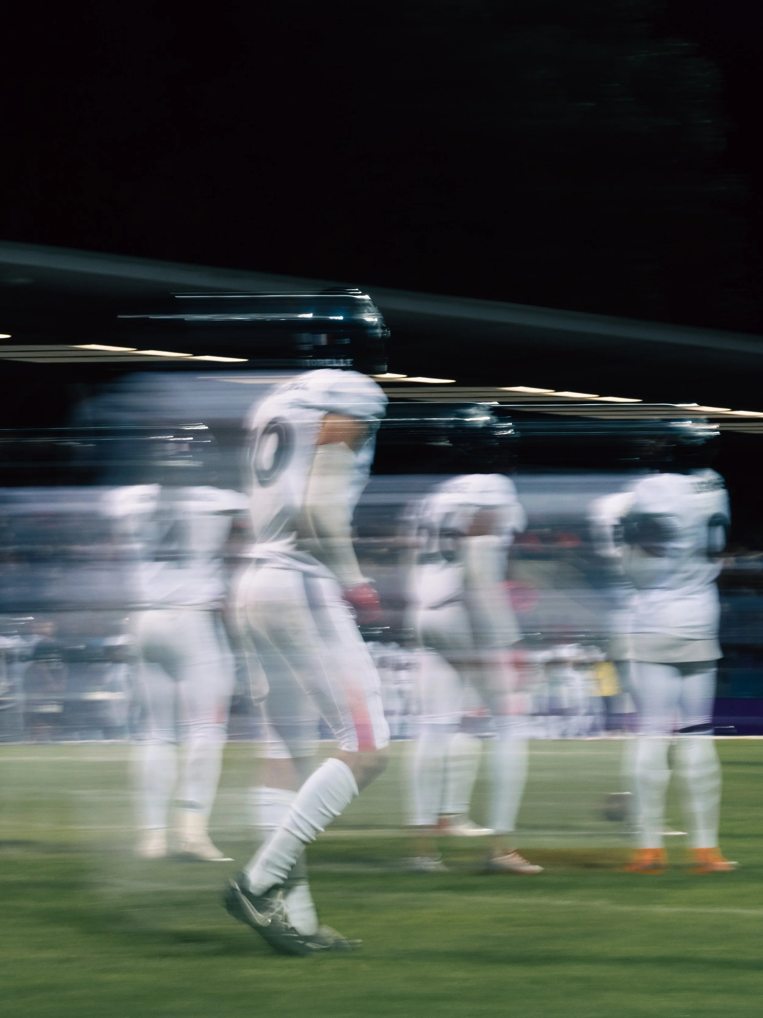 Fotografie eines American Footballspielers der Paris Musketeers in weißen Uniform auf dem Spielfeld während eines Spiels in der Nacht mit Flutlicht. Das Spiel war in der European Football Alliance. Sportfotografie bei der Frankfurt Galaxy.