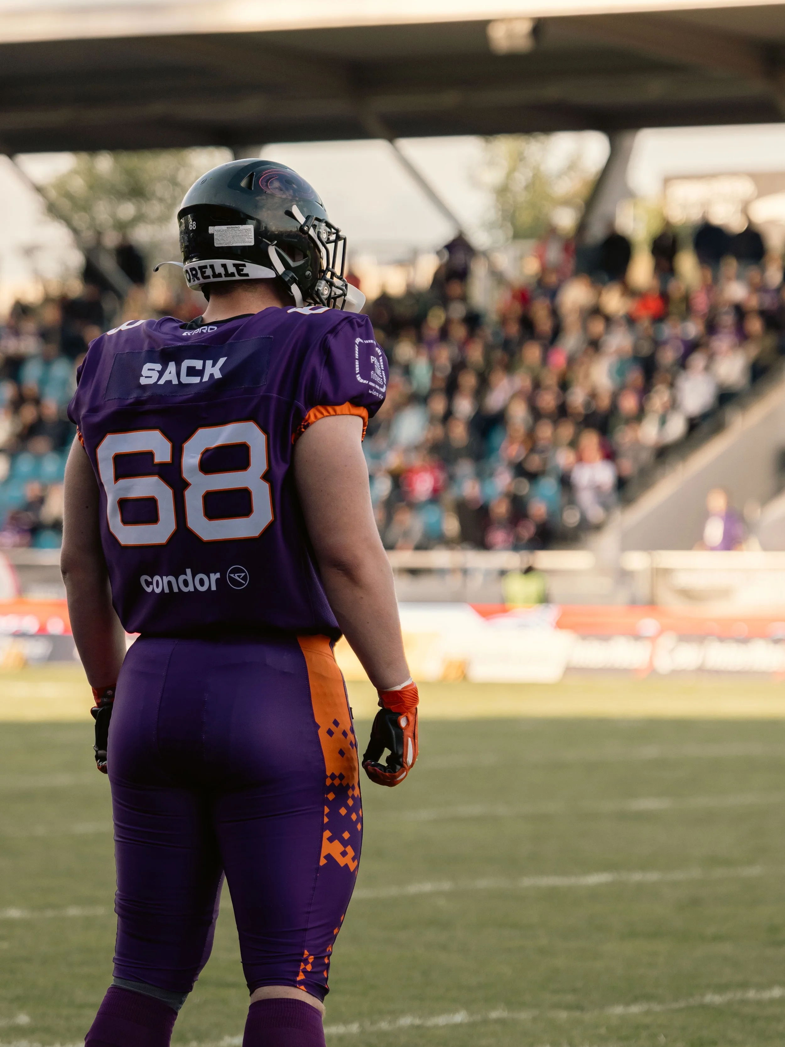 Footballspieler der Frankfurt Galaxy in lila Uniform mit der Nummer 68, mit Helm auf dem Spielfeld vor einer Zuschauertribüne. Sportfotografie bei der Frankfurt Galaxy.