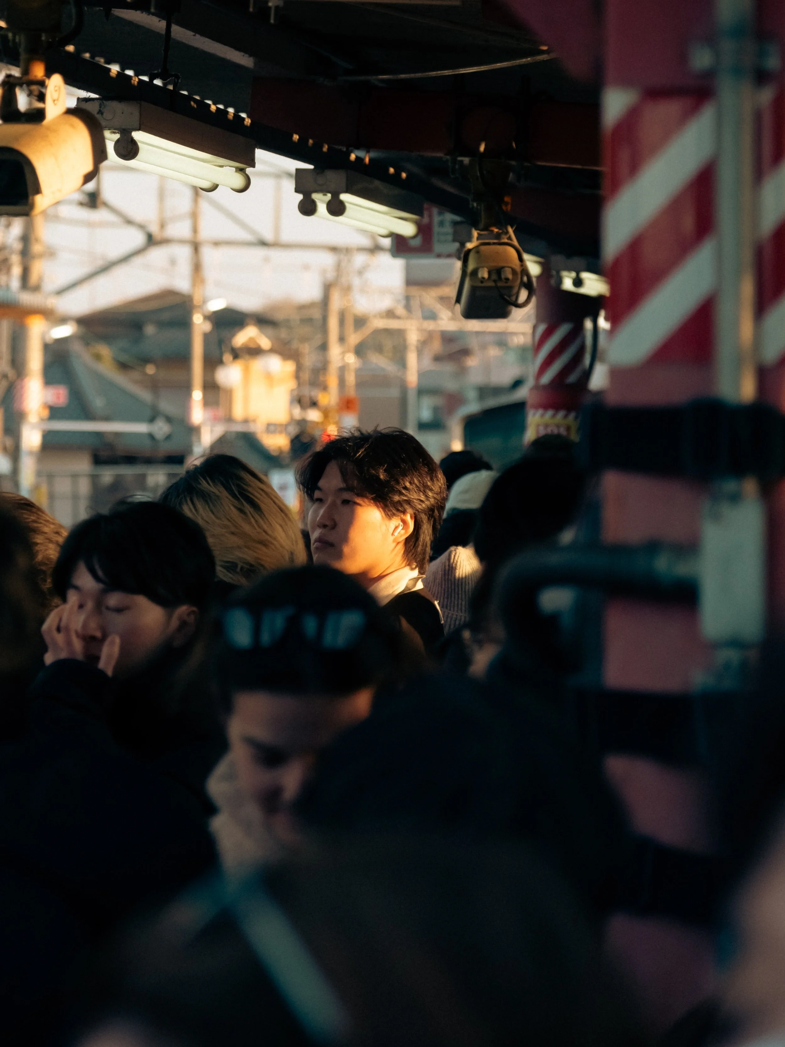 Menschenmenge wartet an einer Haltestelle während der Dämmerung in Japan.