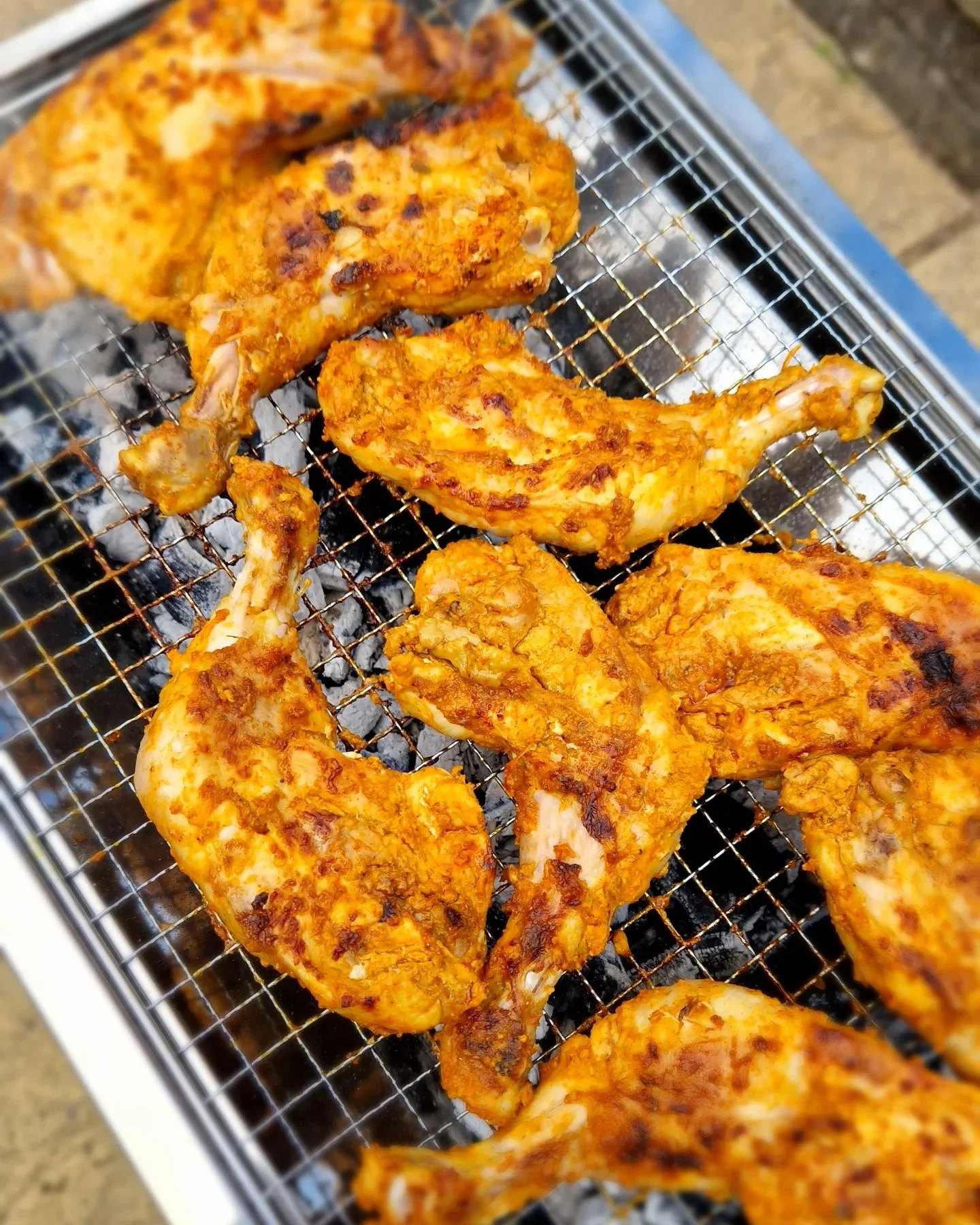 Grilled chicken drumsticks with a golden-brown, spicy seasoning resting on a wire rack.