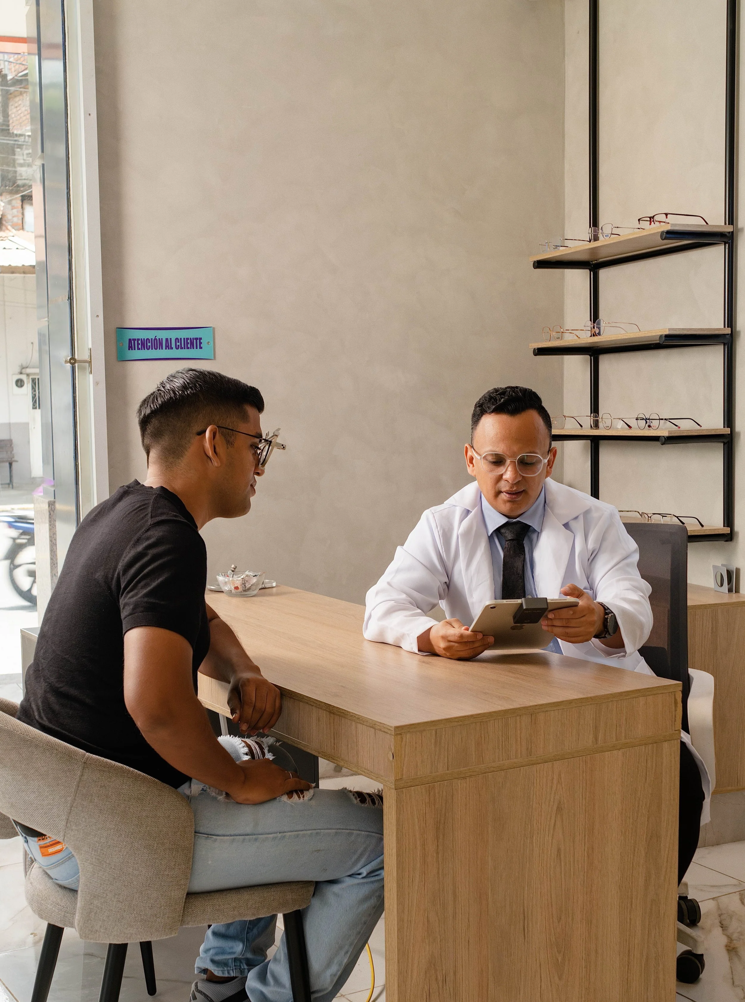 Paciente en consulta con el oftalmólogo en una clínica, mientras observa un dispositivo digital para revisión visual.