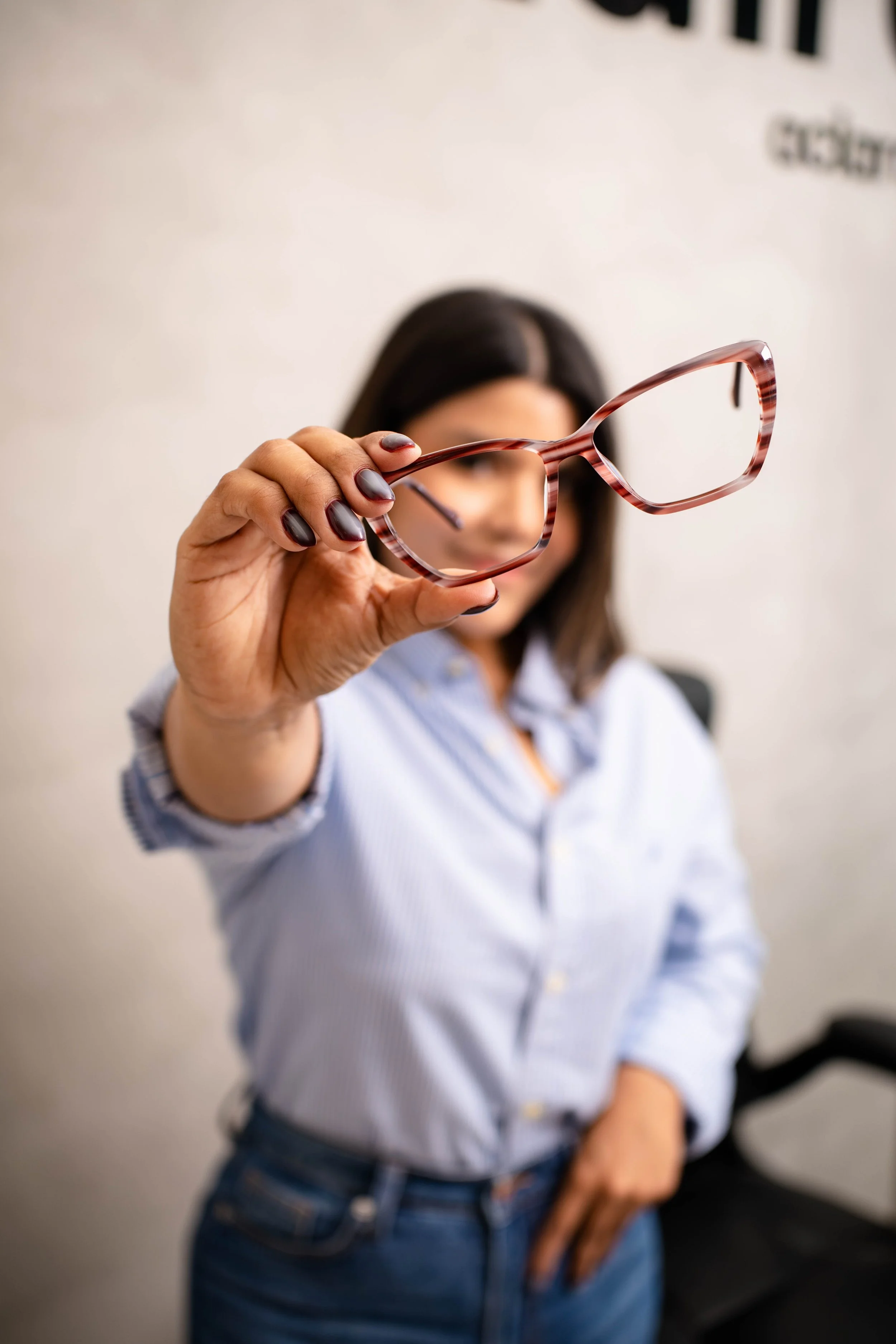 Mujer sosteniendo unos lentes de vista con patrón de carey en primer plano.